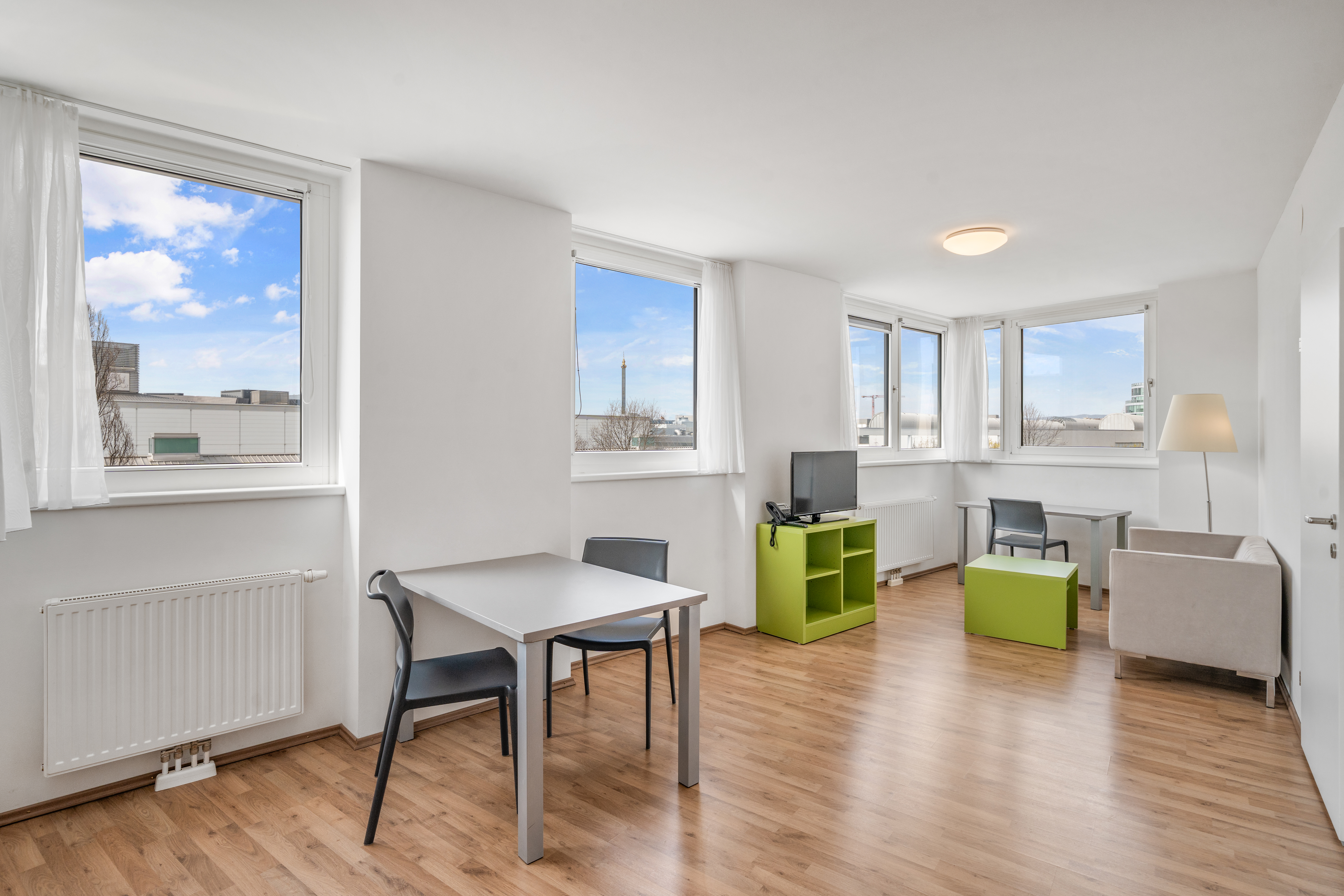 Wohn- und Arbeitsbereich mit großem Essbereich und Fensterfront in einem möblierten Room4Rent L Balcony Apartment in Wien