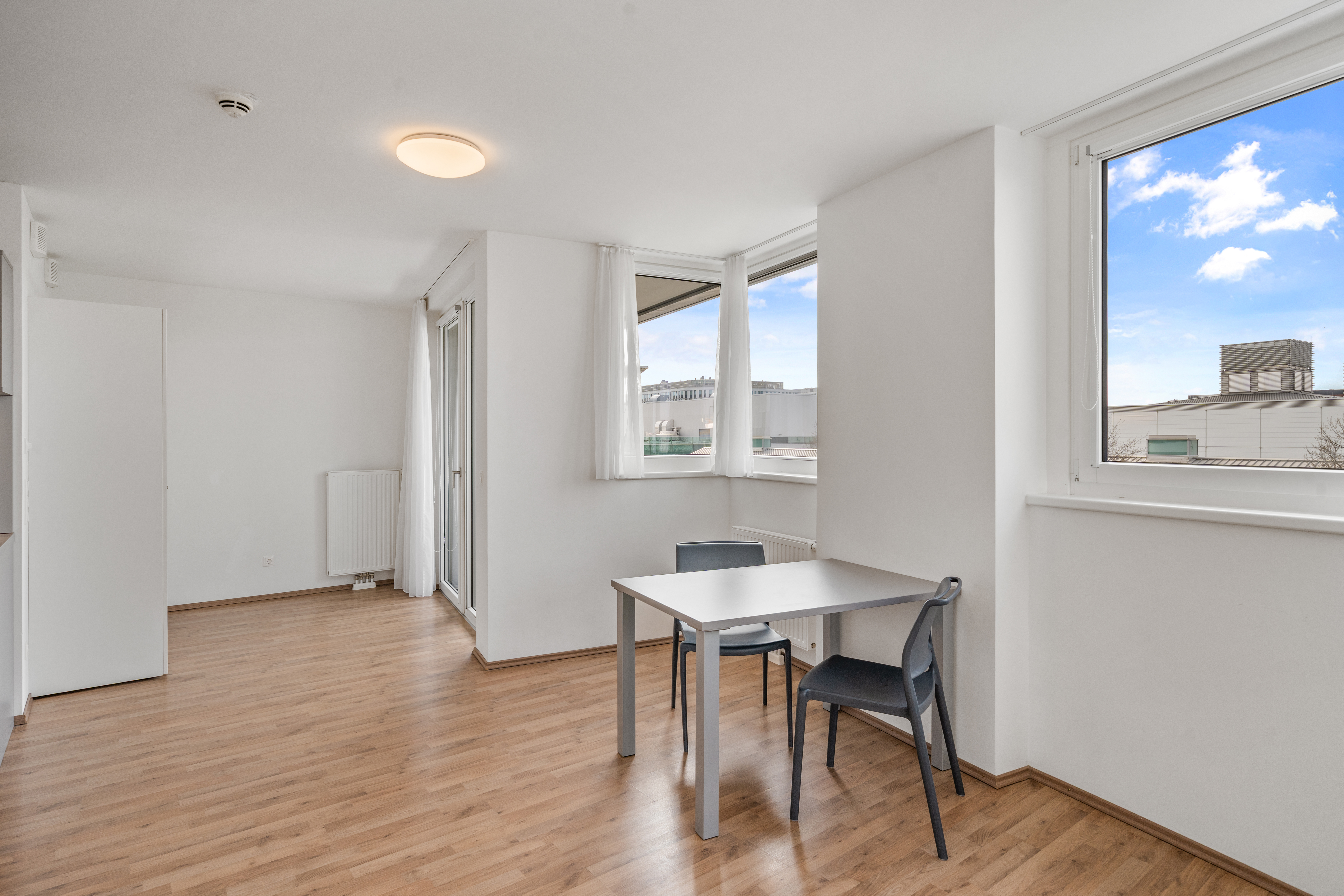 Essbereich mit Tisch und Stühlen und Fensterblück in einem möblierten Room4Rent L Balcony Apartment in Wien