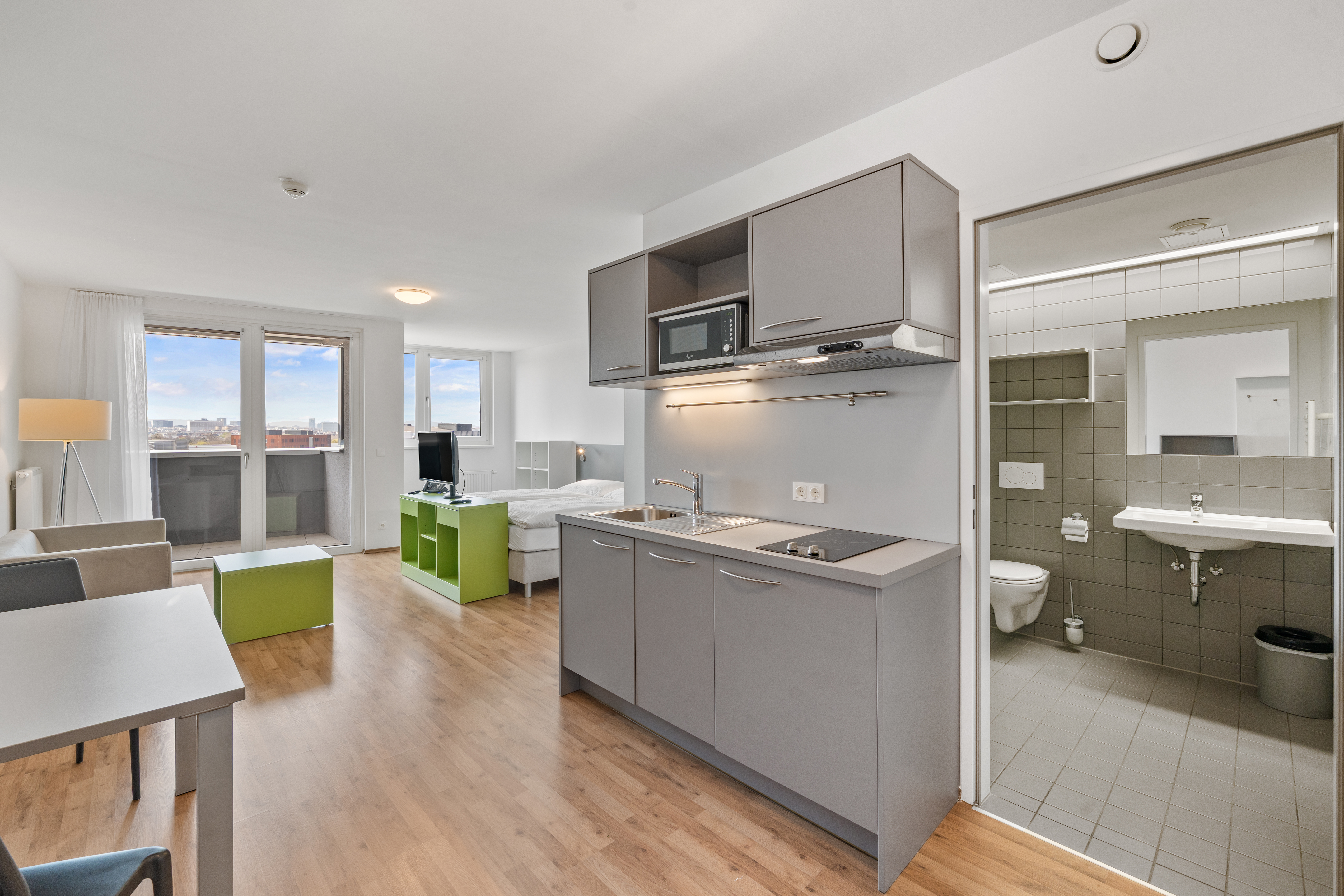 Möbliertes Apartment mit Küchenzeile, Wohnbereich, Arbeitsplatz und angrenzend sichtbarem Badezimmer im Room4Rent Standort Messenord