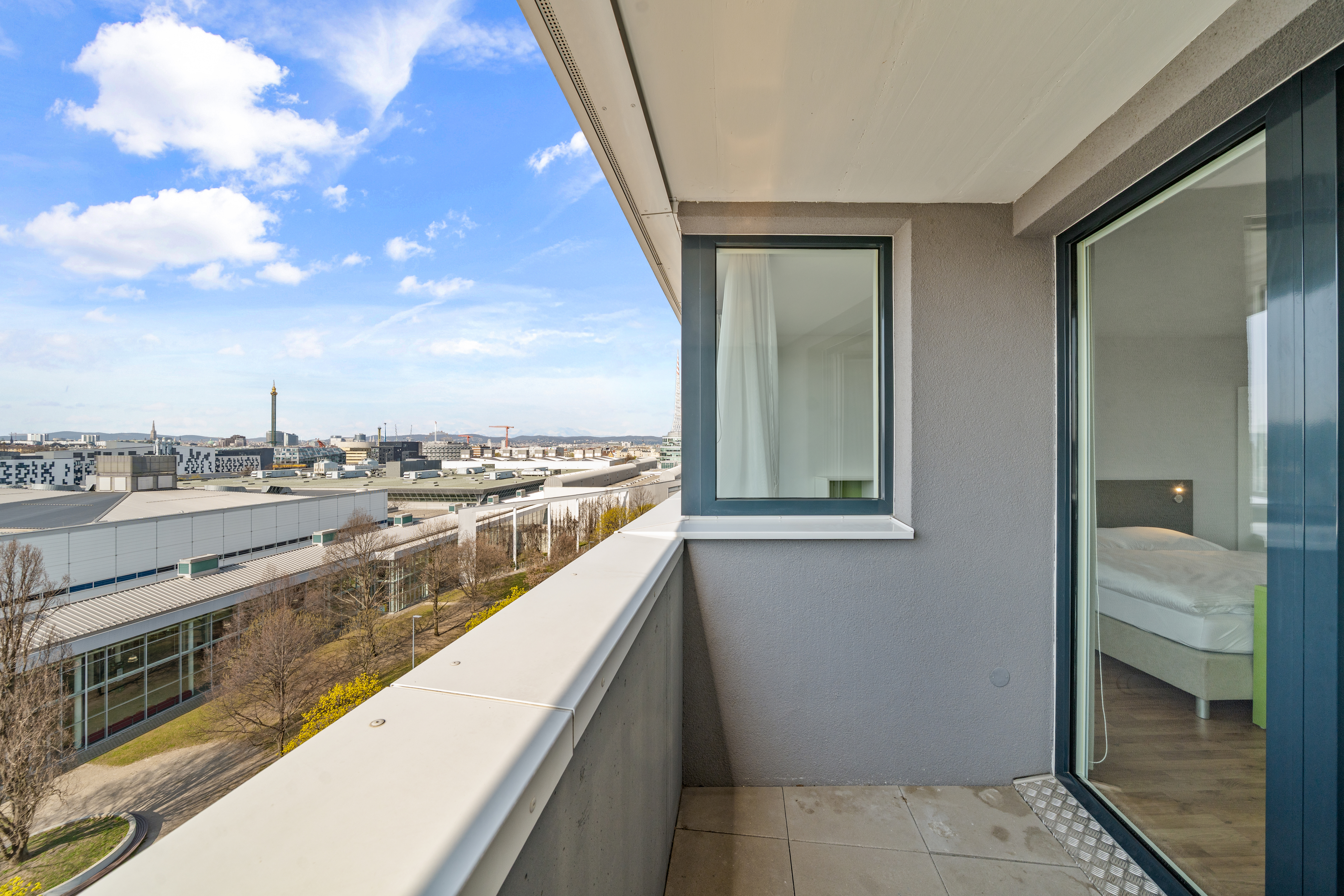 Balkon eines möblierten Apartments mit Blick über Wien, im Hintergrund Donau und Stadtpanorama