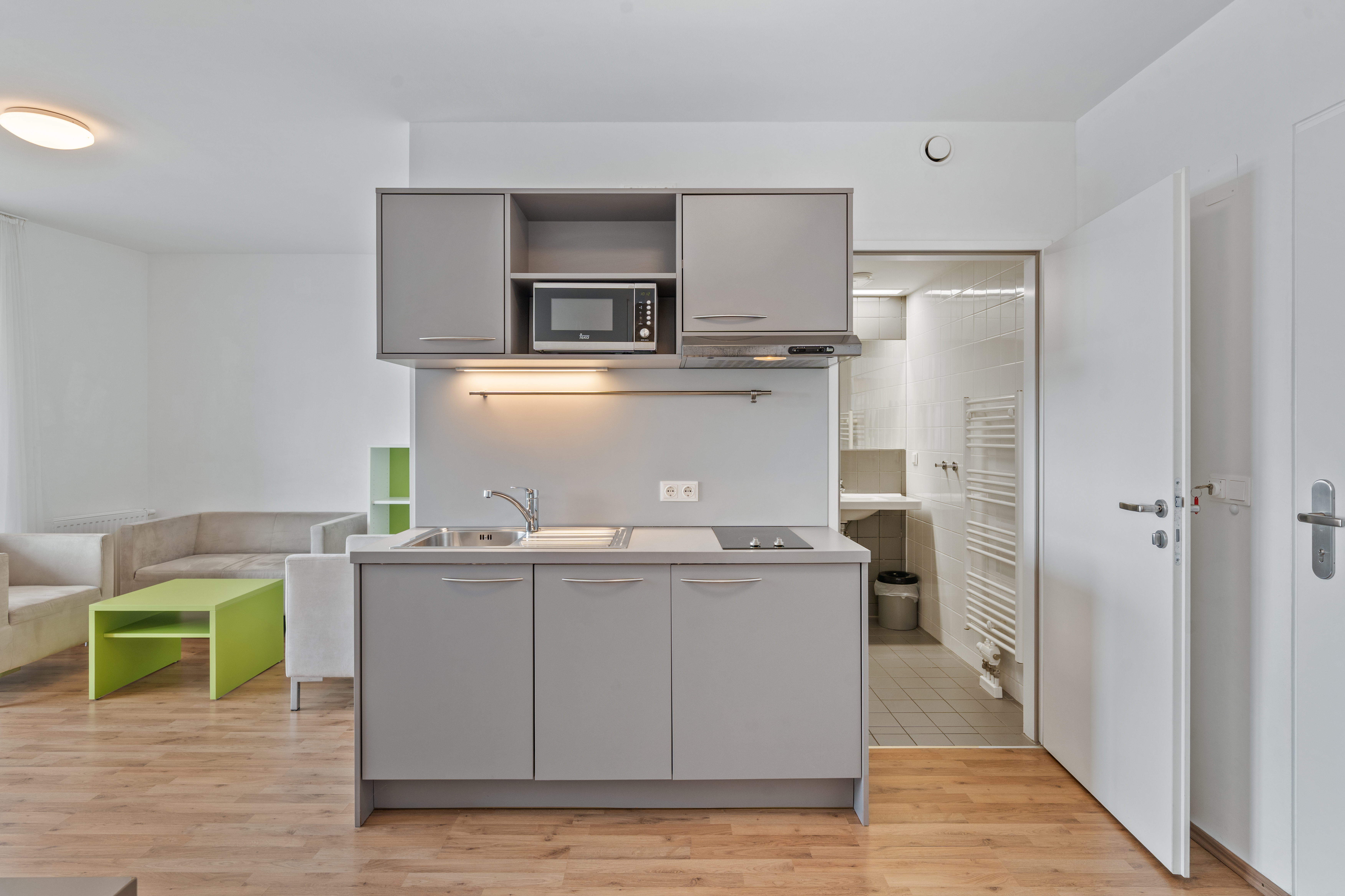 Offene Wohnküche eines leeren XL-Apartments mit Kochinsel, grünem Couchtisch und Wohnbereich