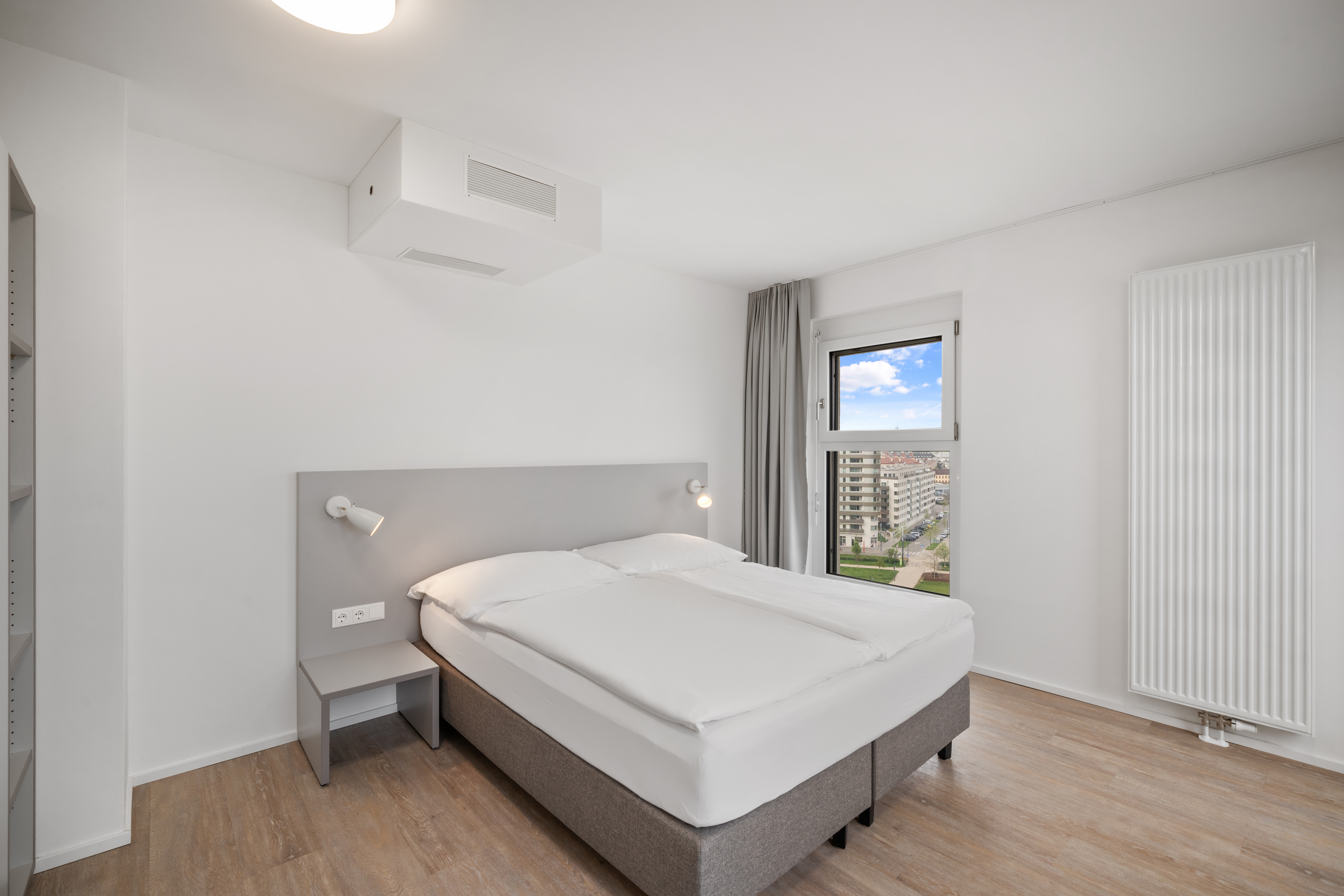 Schlafzimmer mit Doppelbett und Fenster mit Stadtblick im möblierten Apartment Typ L der MusicBox