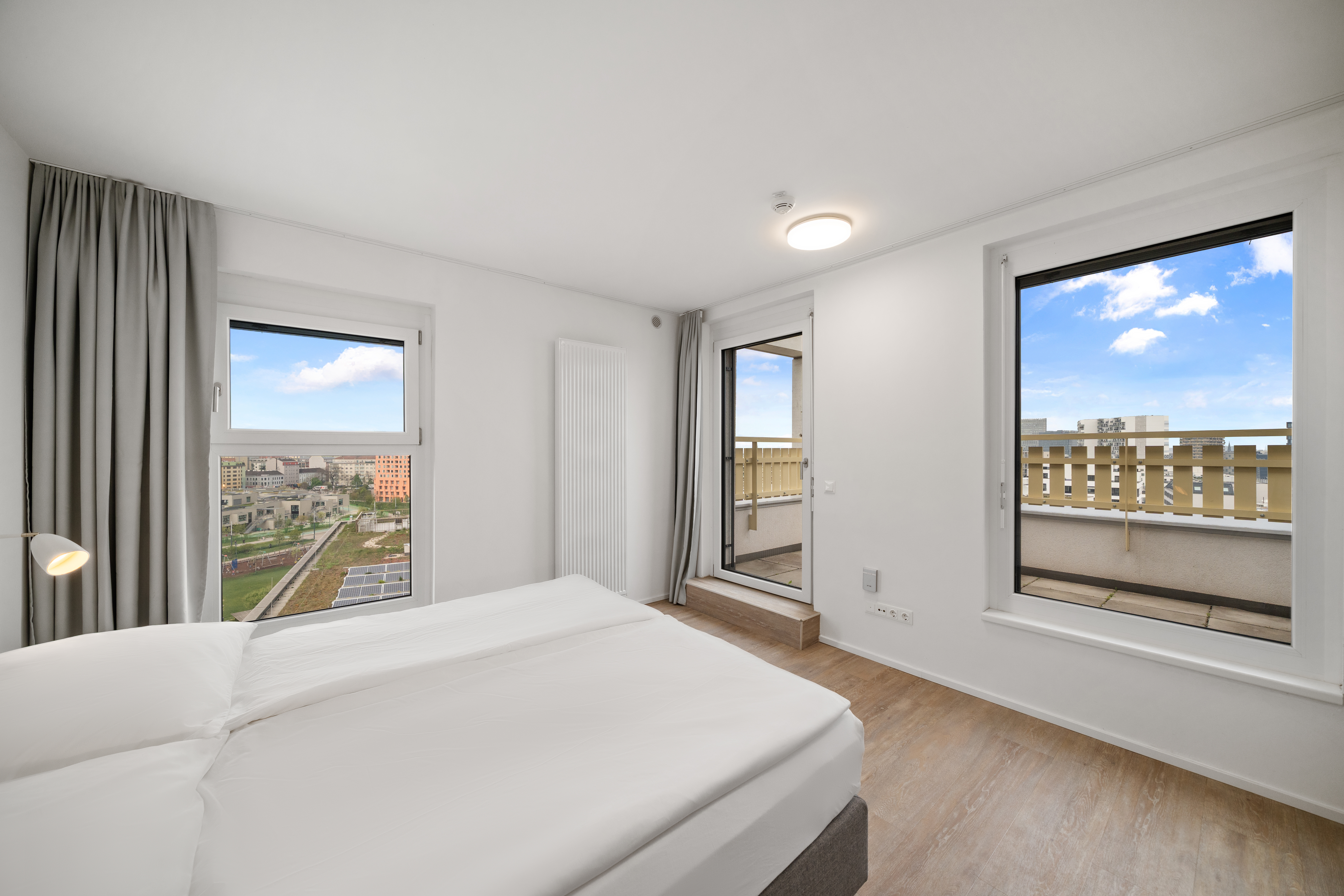 Helles Schlafzimmer mit Doppelbett und Balkonzugang im Room4Rent Apartment Typ L
