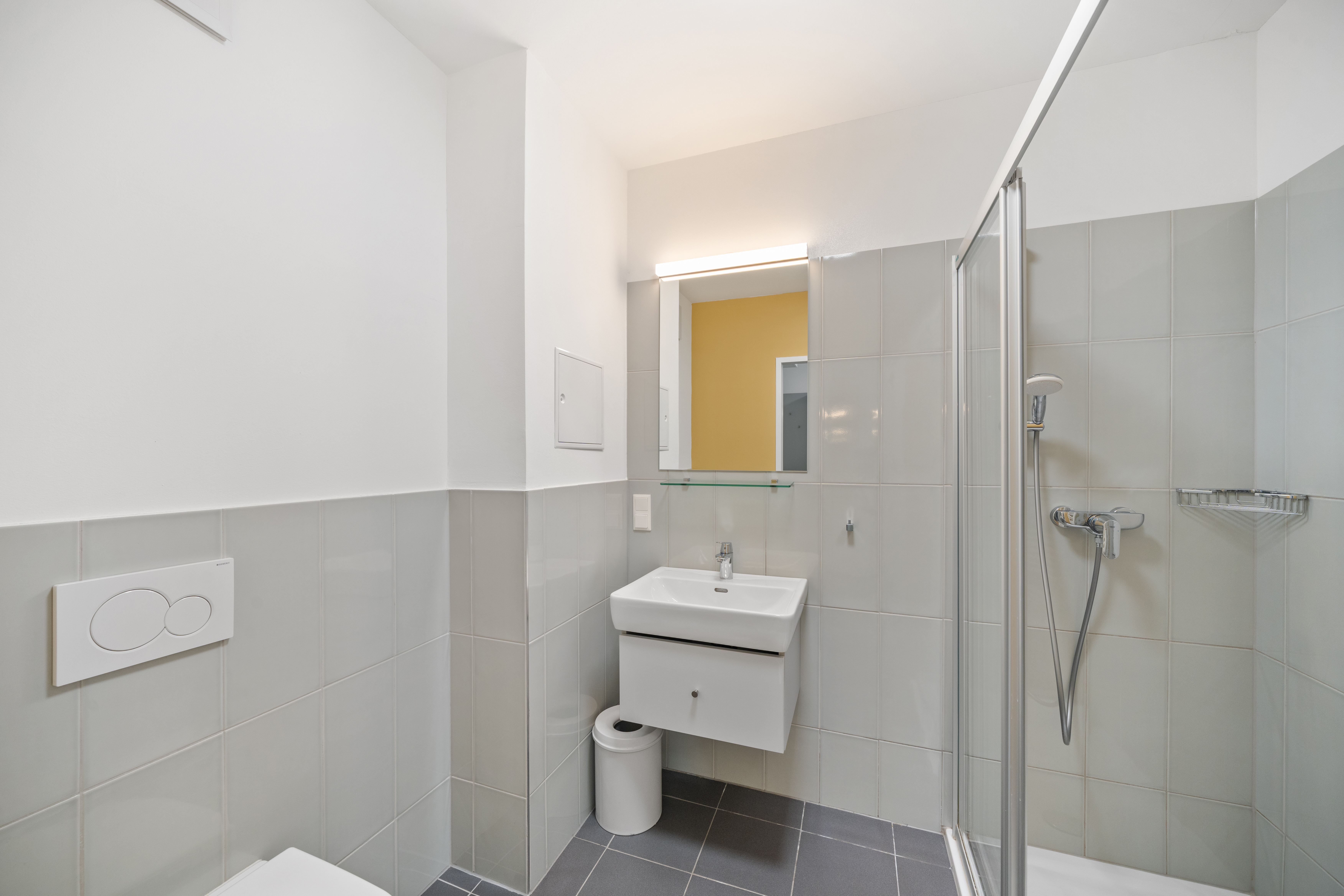 Modernes Badezimmer mit weißem Waschtisch, Spiegel, Toilette und begehbarer Dusche