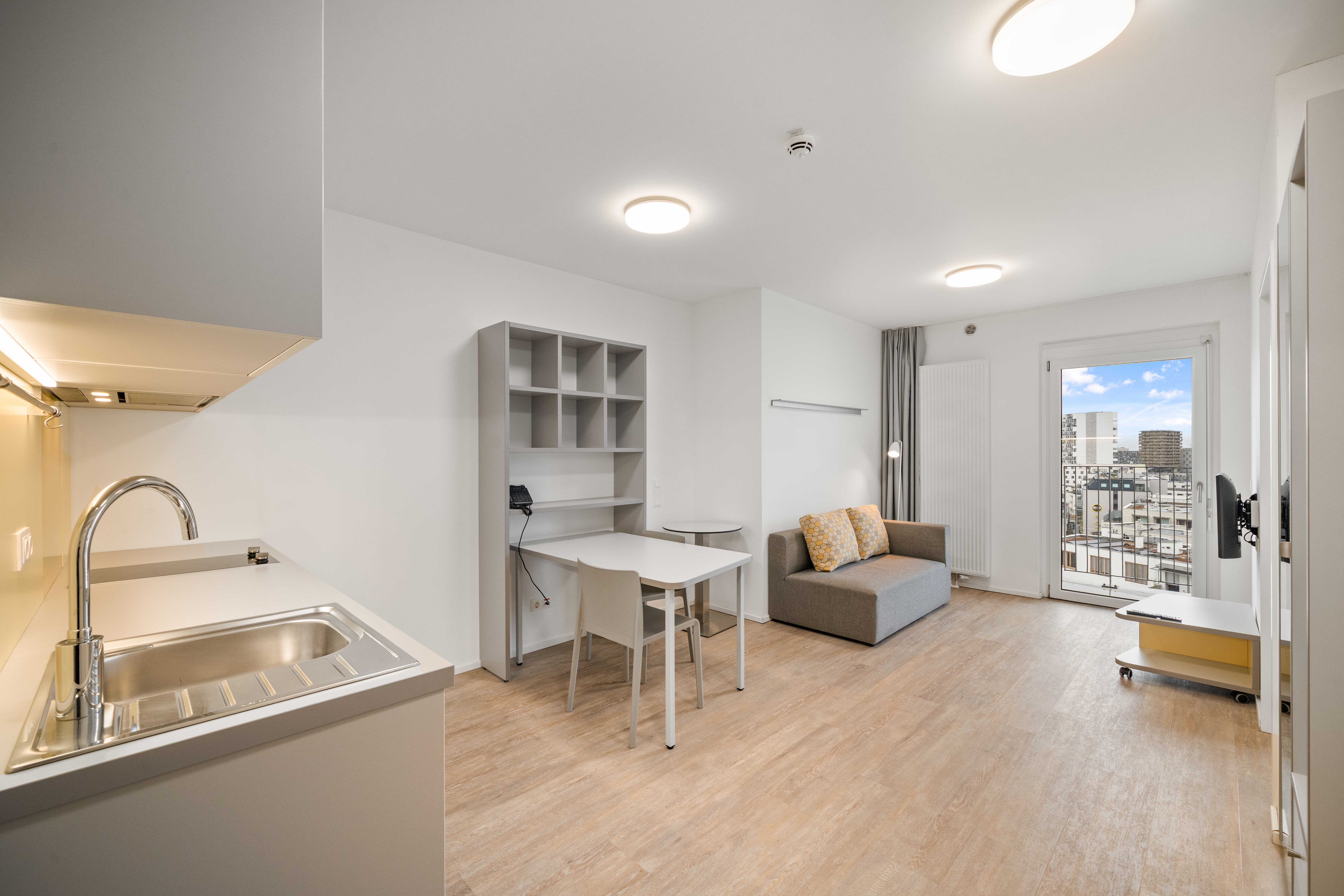 Offener Wohnbereich mit Küche, Esstisch und Arbeitsplatz in einem Room4Rent Apartment