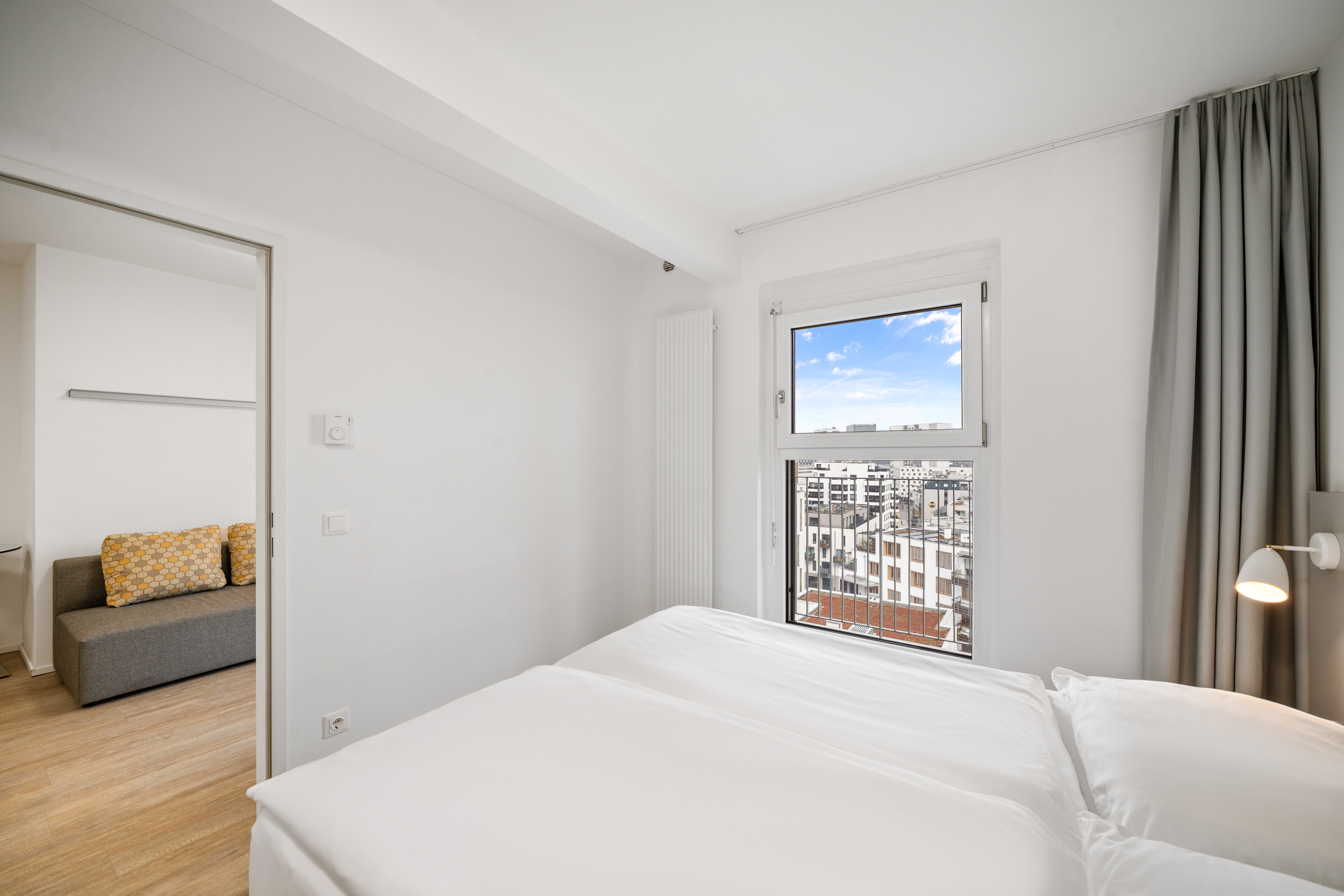 Schlafbereich mit Fenster und Blick über Wien in einem Room4Rent Apartment mit Balkon