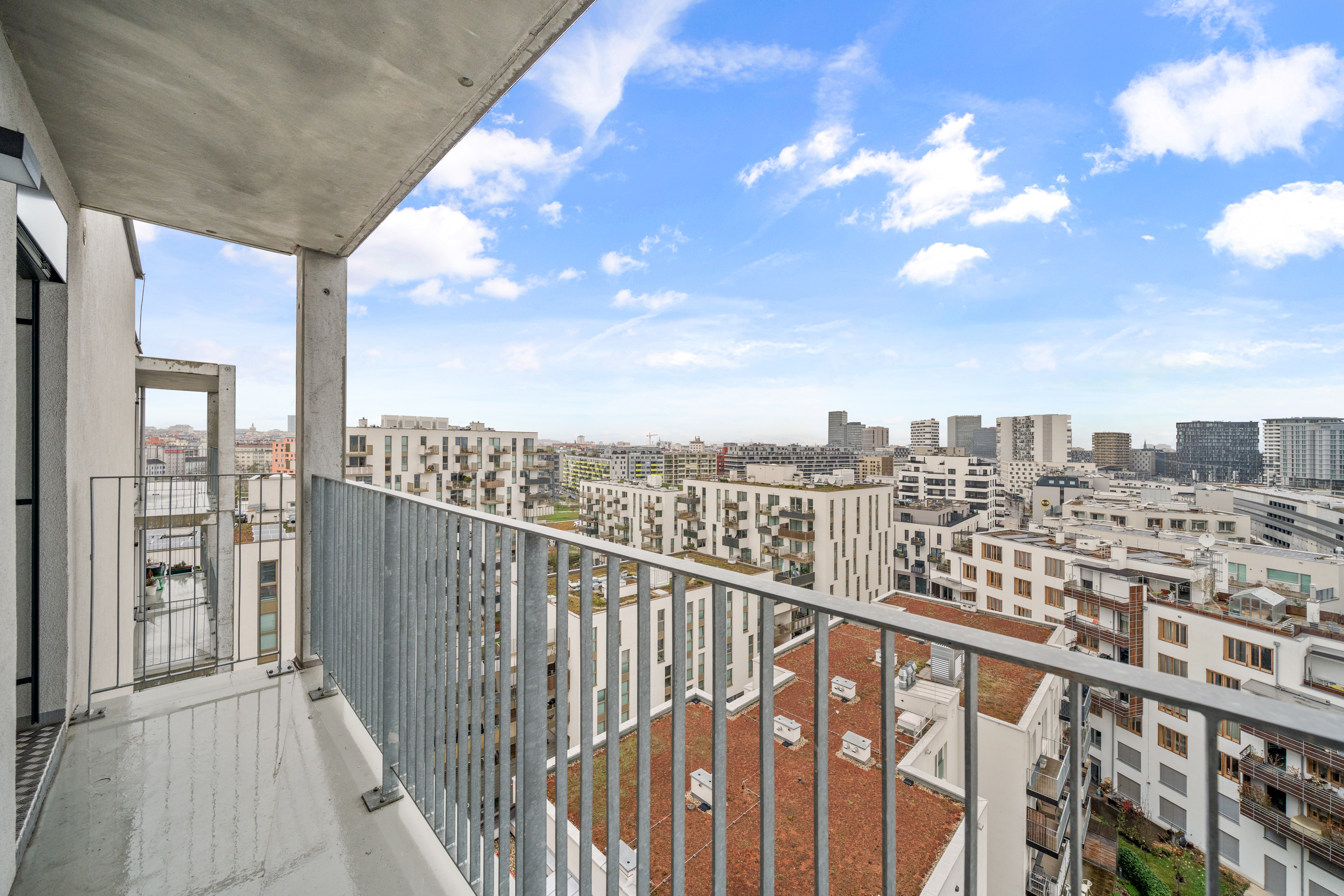Balkon mit Ausblick über urbane Wohnhäuser und Skyline bei blauem Himmel