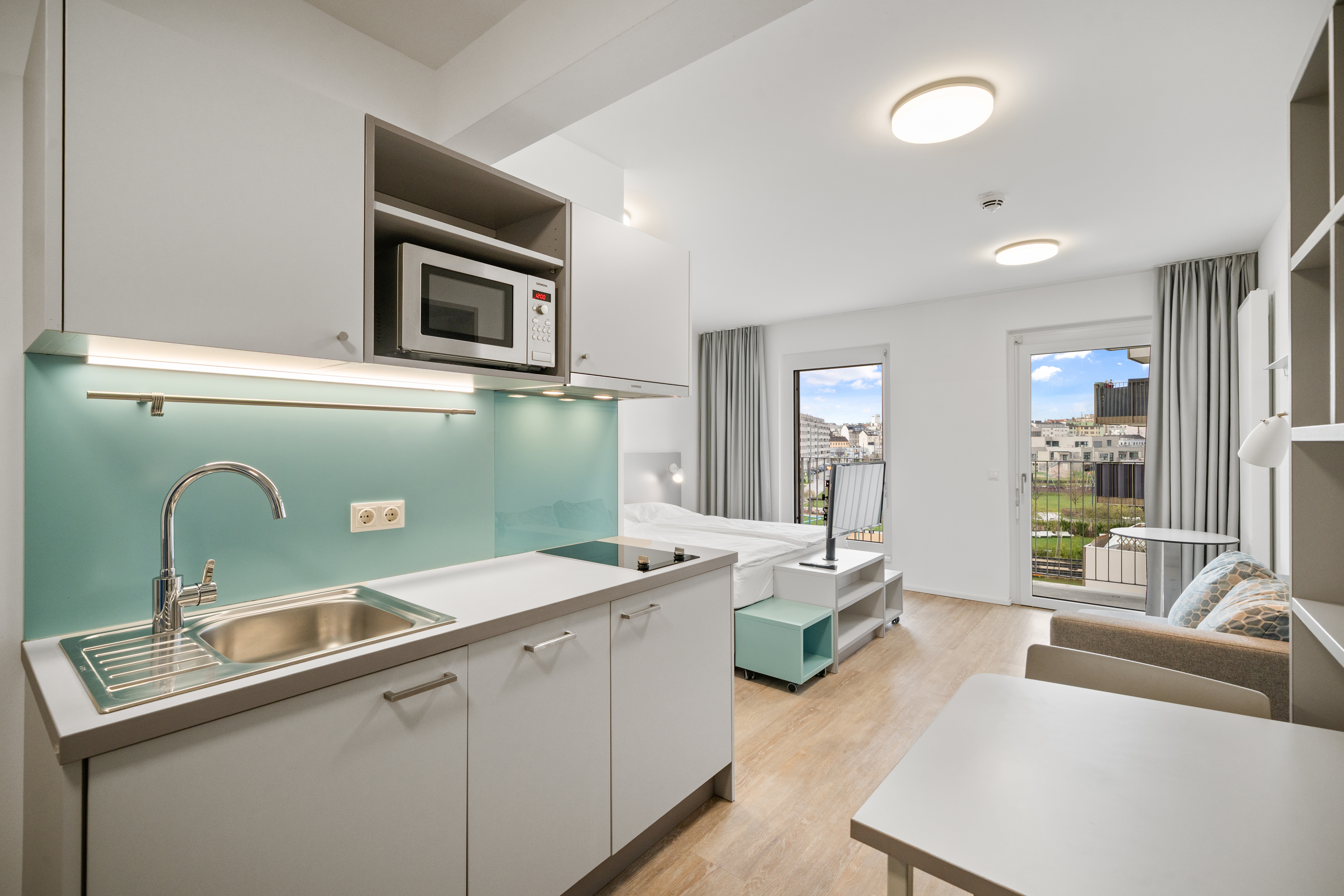 Wohnküche mit Essbereich und türkisem Fliesenspiegel in einem möblierten Serviced Apartment der MusicBox Wien
