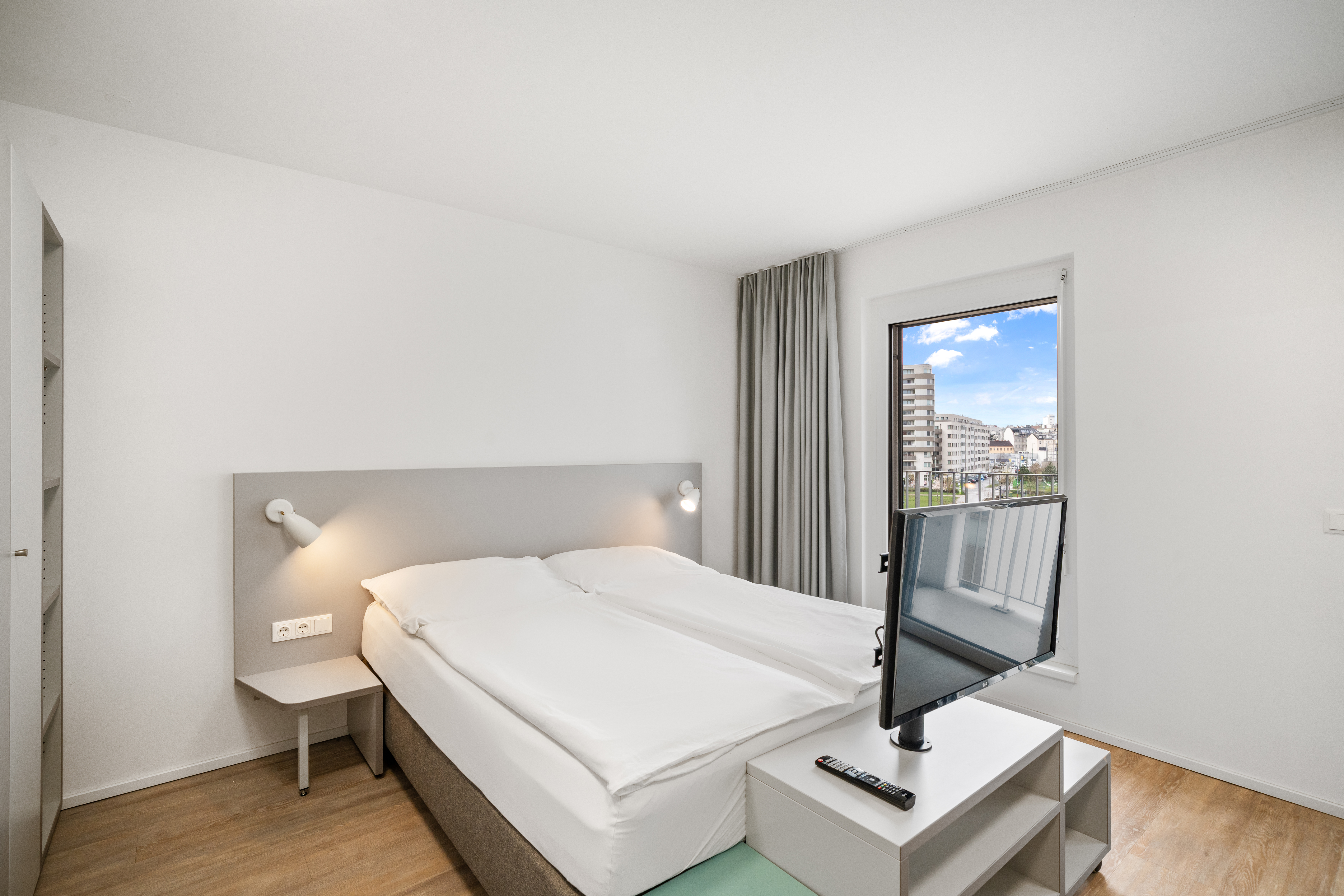 Schlafbereich mit Boxspringbett und Fernseher in einem möblierten Apartment der MusicBox Wien