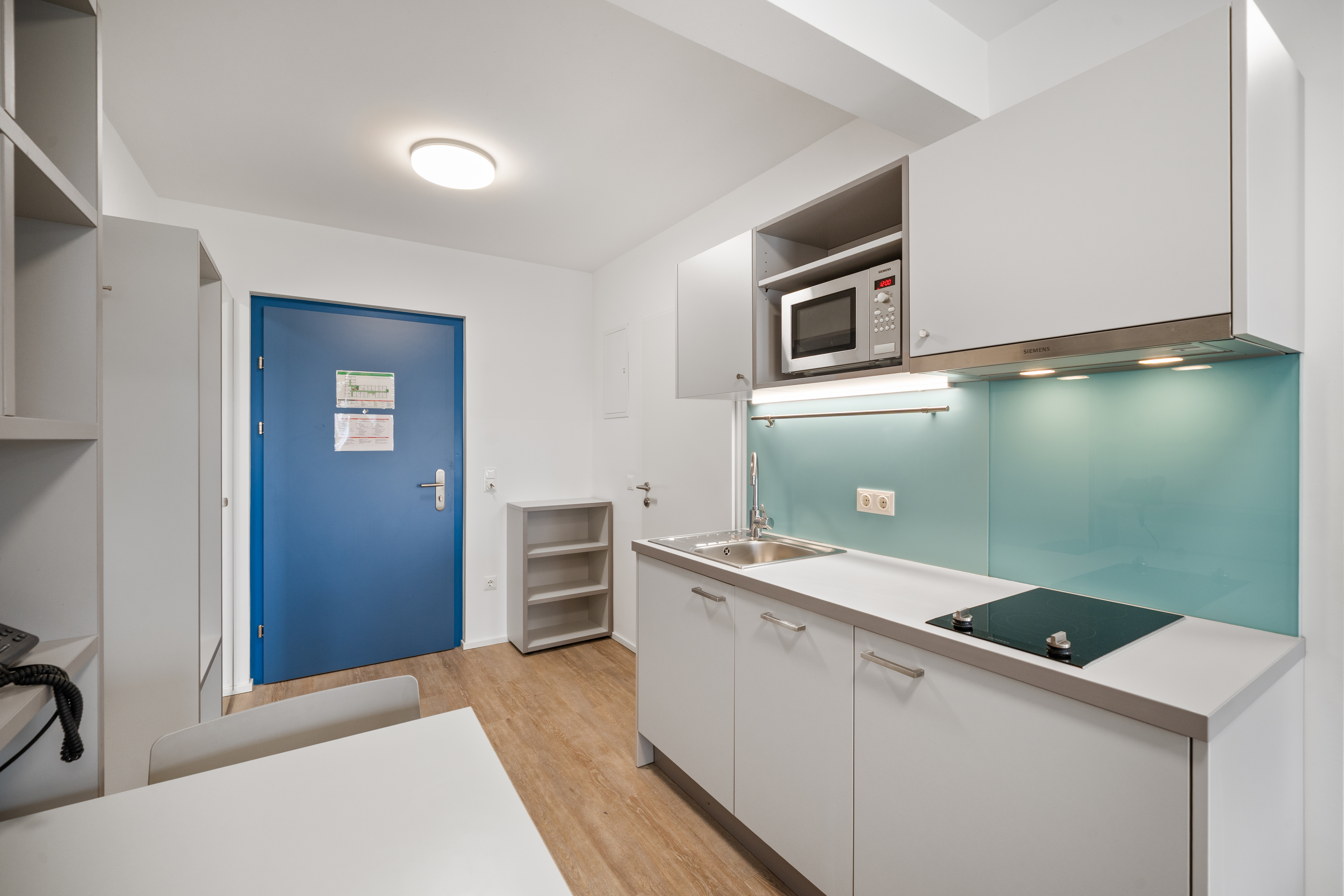 Kleine Küchenzeile mit Arbeitsplatte und modernem Fliesenspiegel in einem möblierten Apartment der MusicBox Wien