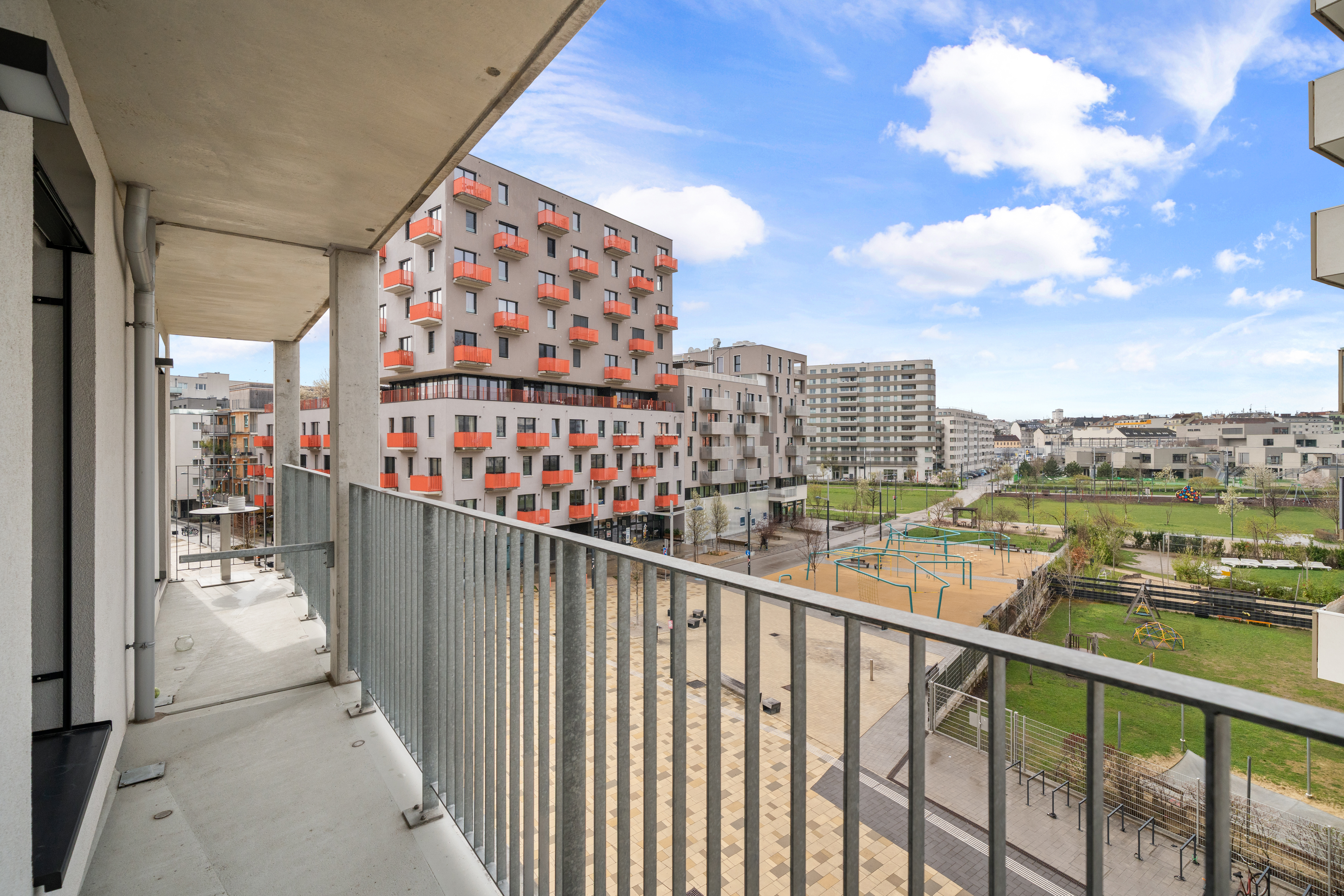 Balkon mit Stahlgeländer und Blick auf Grünfläche, Spielplatz und moderne Wohngebäude im Serviced Apartment MusicBox