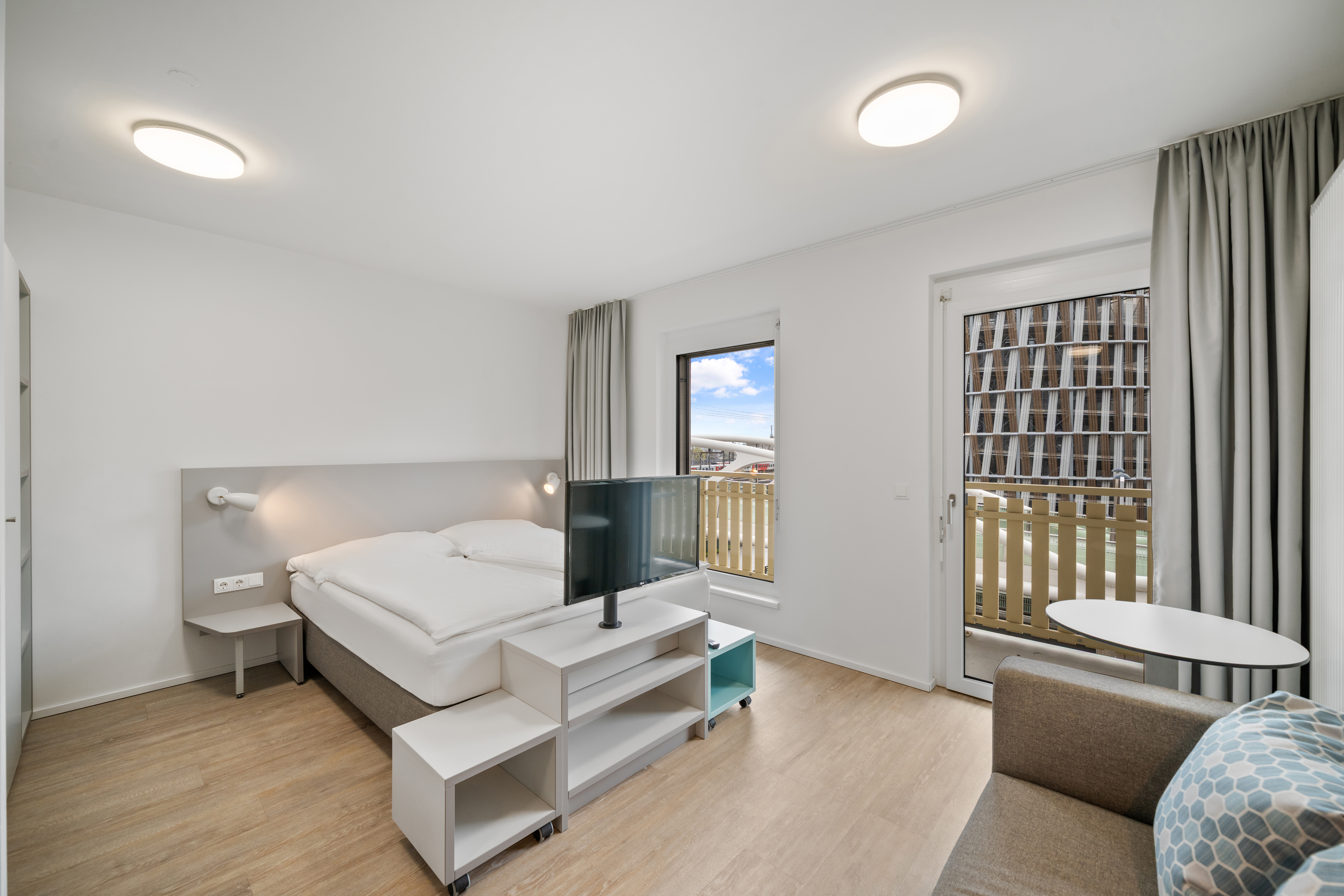 Schlafbereich mit Flachbildschirm und Balkon in einem Room4Rent XS Balcony Serviced Apartment