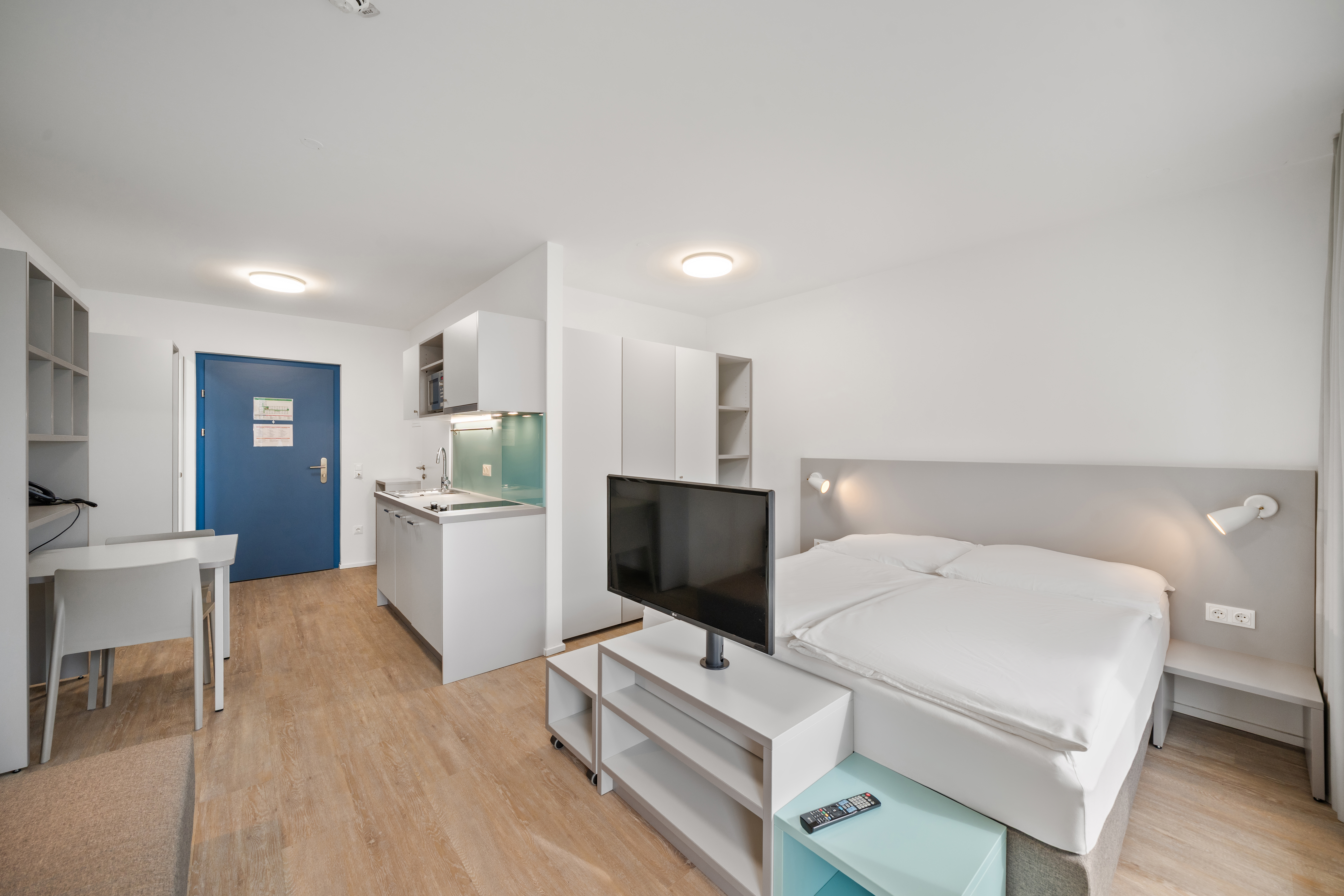 Moderner Wohnbereich mit Kitchenette und Bett in einem Room4Rent möblierten Apartment