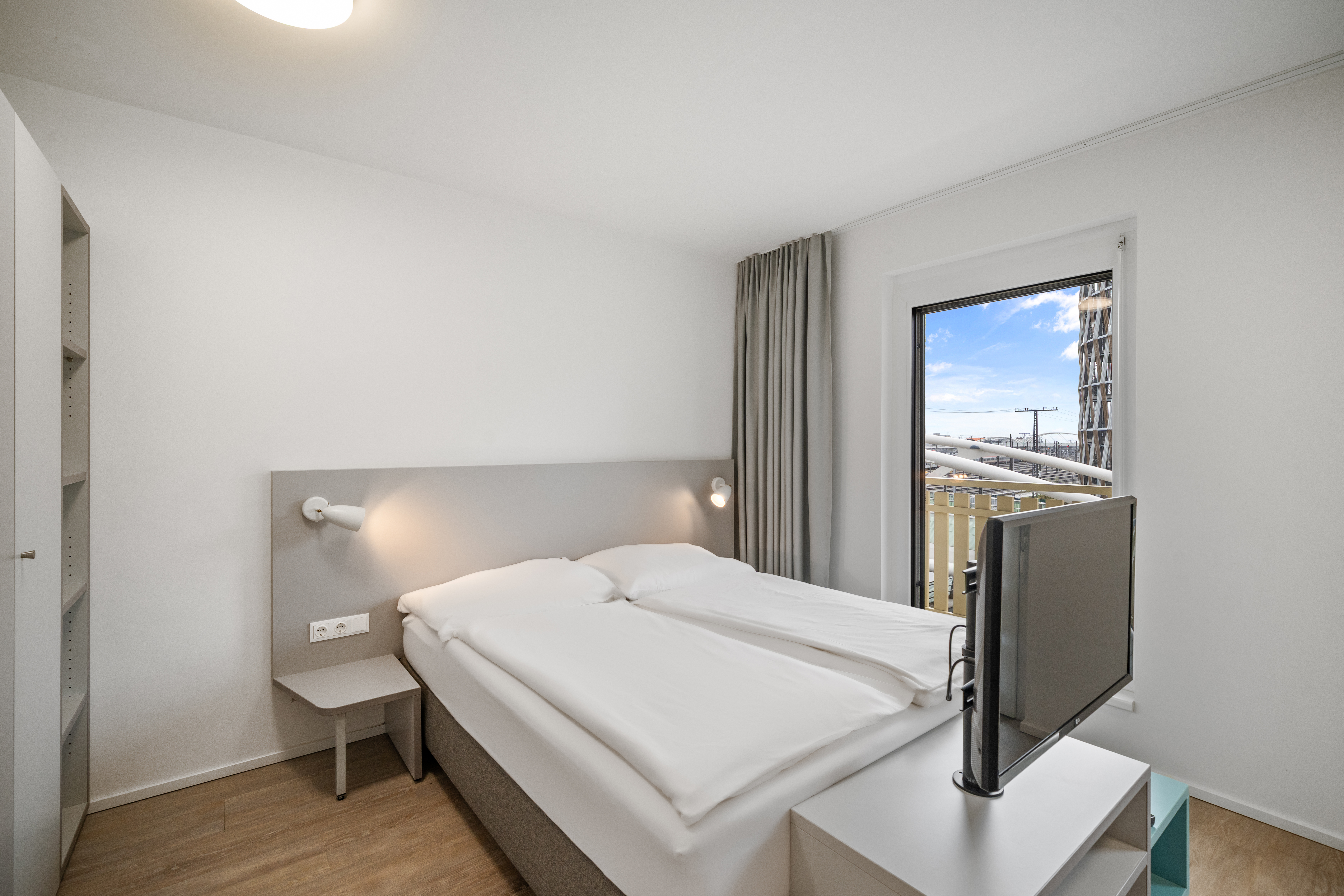 Schlafbereich mit Doppelbett und Balkonausblick in einem Room4Rent XS Balcony Serviced Apartment in der MusicBox Wien