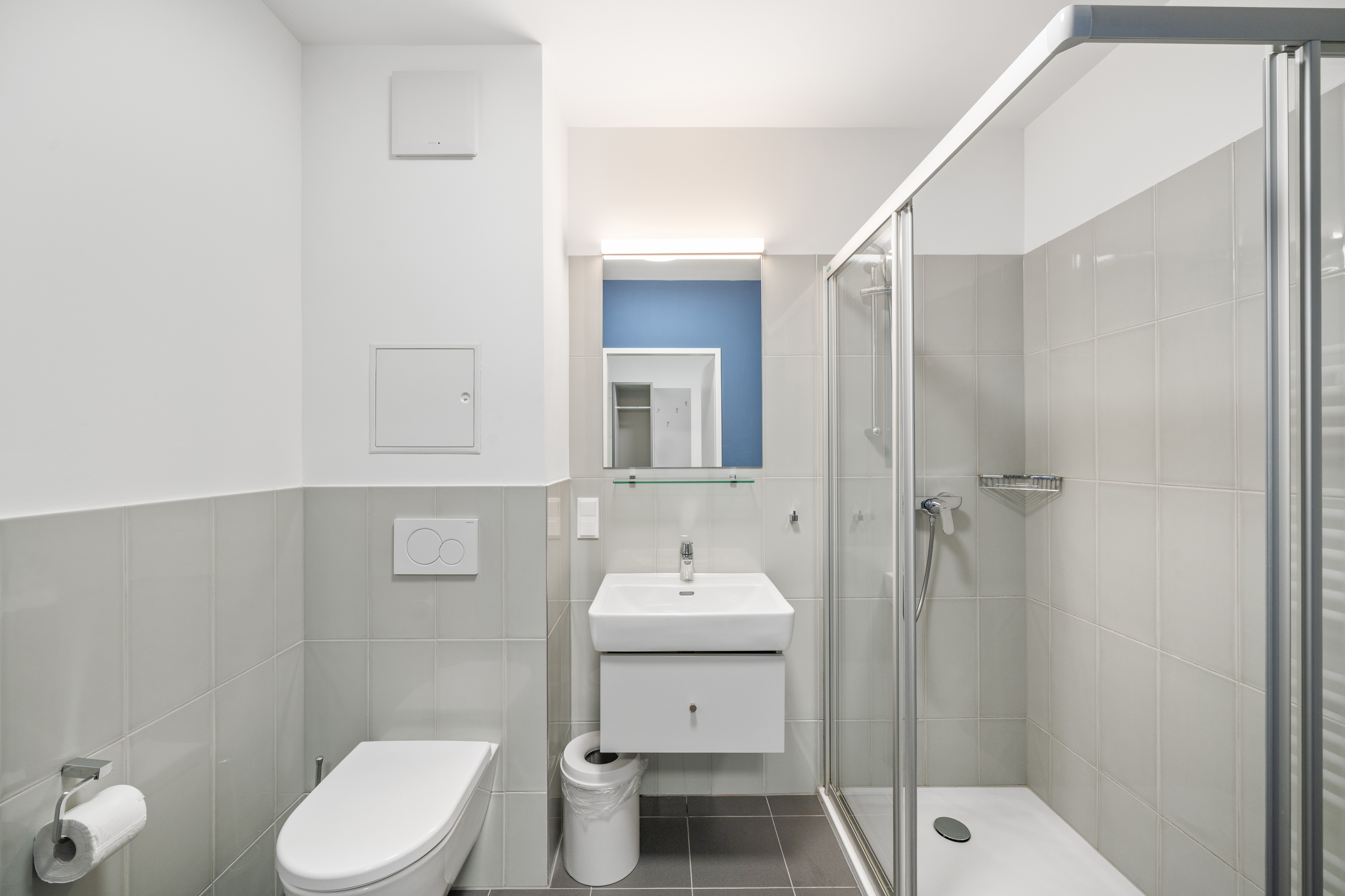 Modernes Badezimmer mit Toilette, Waschbecken und begehbarer Dusche in einem Room4Rent XS Serviced Apartment