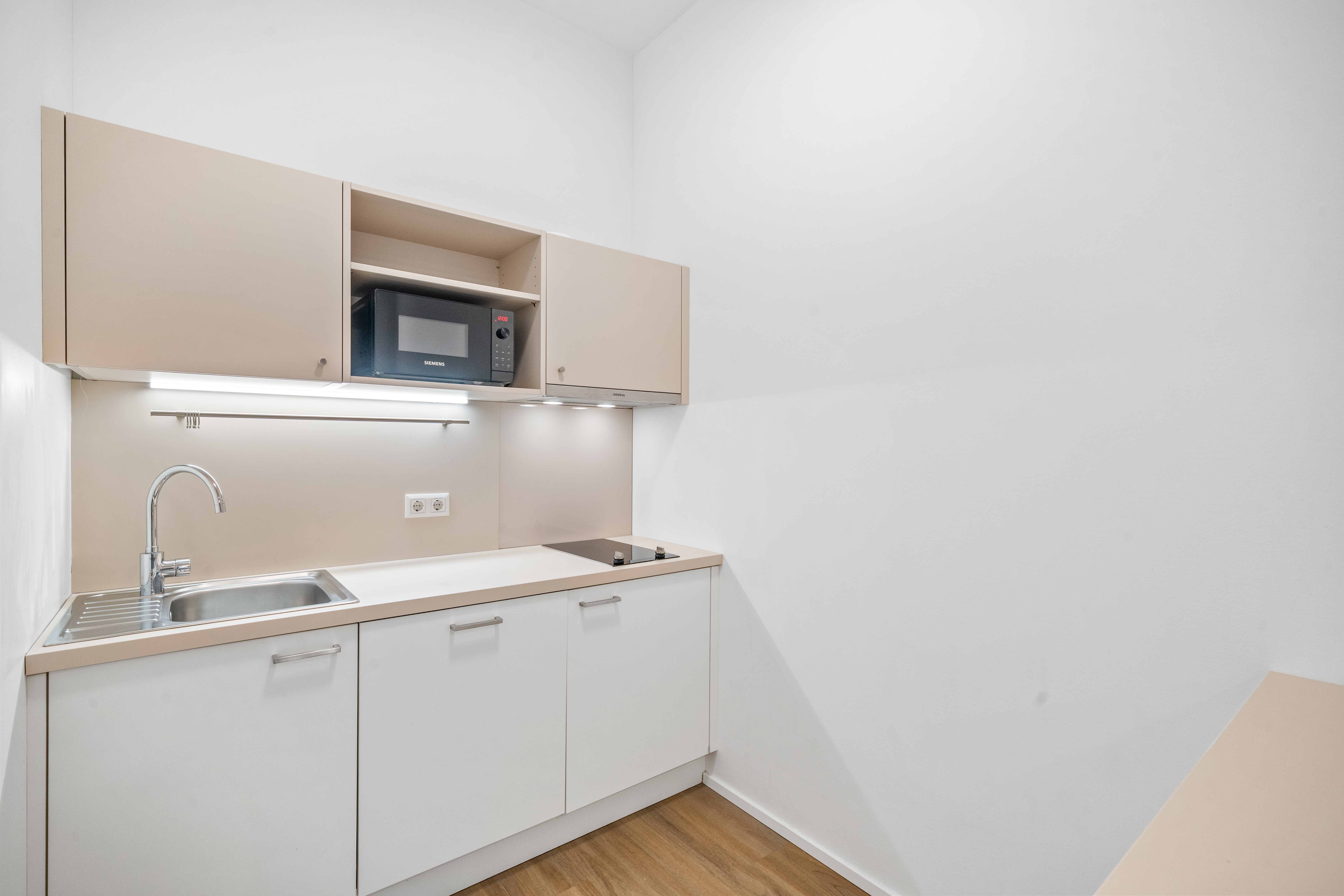 Küche mit Spüle und Mikrowelle in einem Room4Rent Serviced Apartment Typ L im Q-Tower