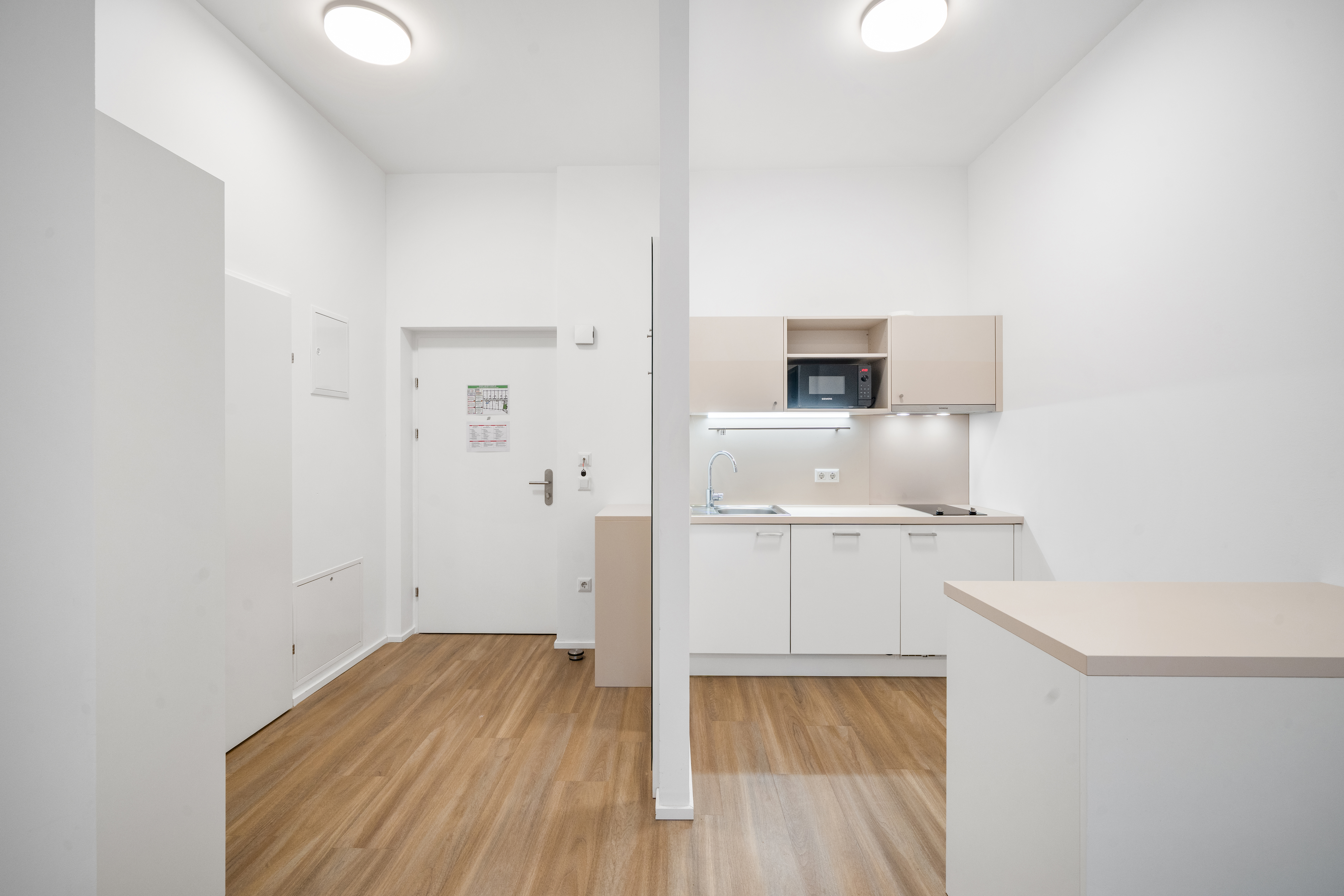 Küchenzeile mit Mikrowelle, Spüle und offenem Essbereich in einem Room4Rent möblierten Apartment Typ L