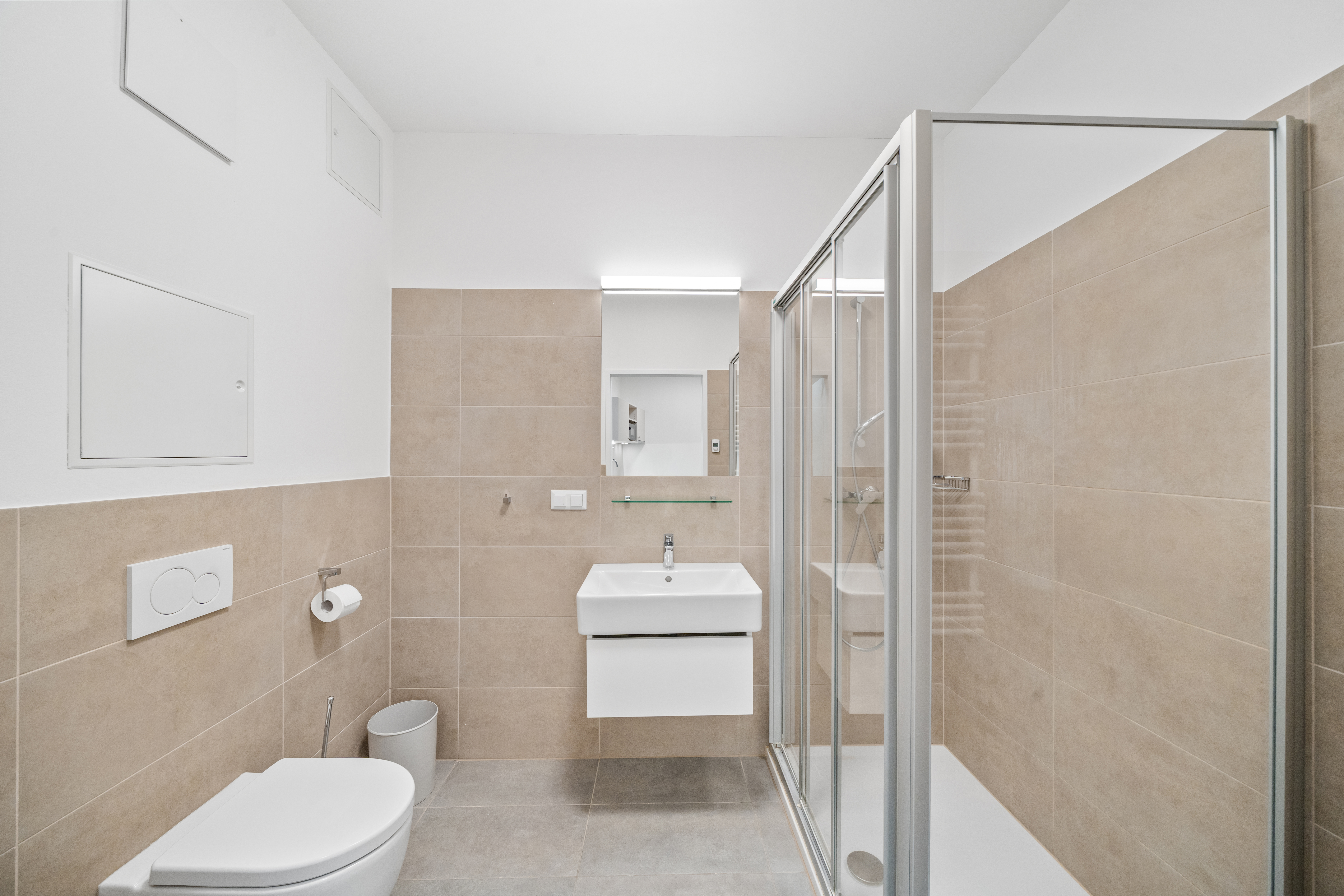 Badezimmer mit Toilette, Waschbecken und ebenerdiger Dusche in einem Room4Rent Apartment Typ L