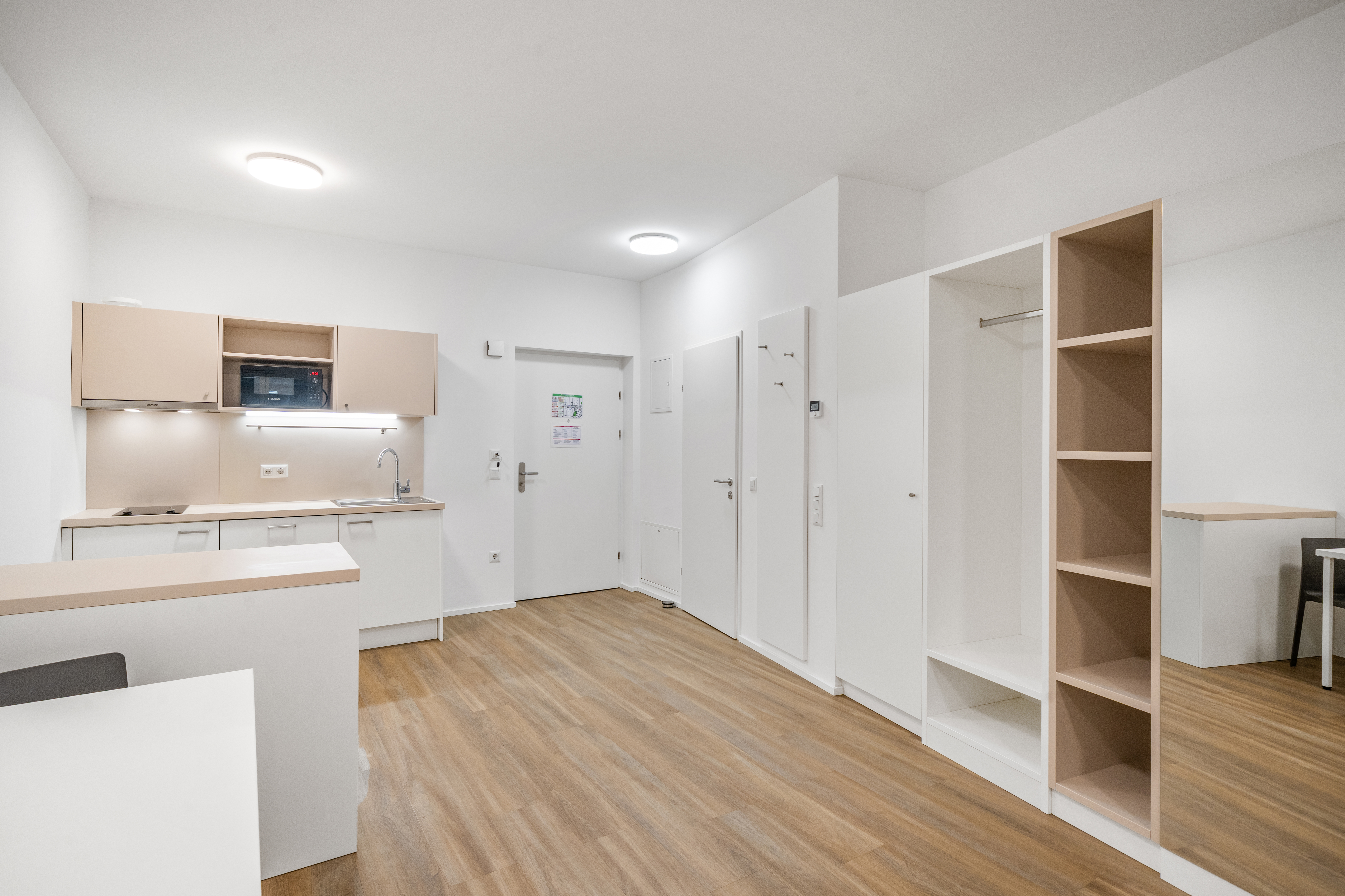 Offener Wohnbereich mit Küche, Essbereich und Regalen in einem Room4Rent Serviced Apartment im Q-Tower