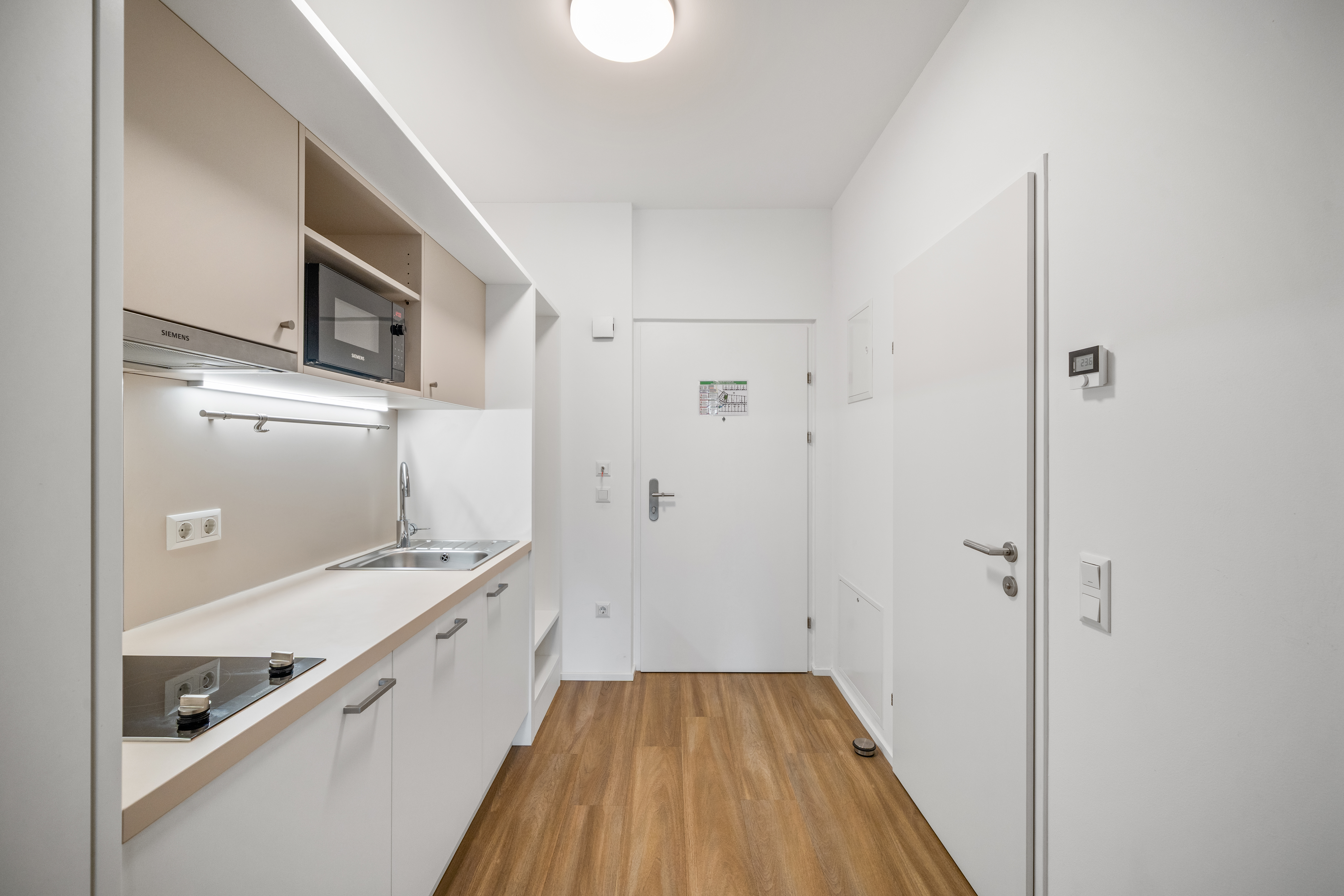 Küchenzeile mit Arbeitsplatte, Mikrowelle und Herd in einem möblierten Serviced Apartment im Q-Tower