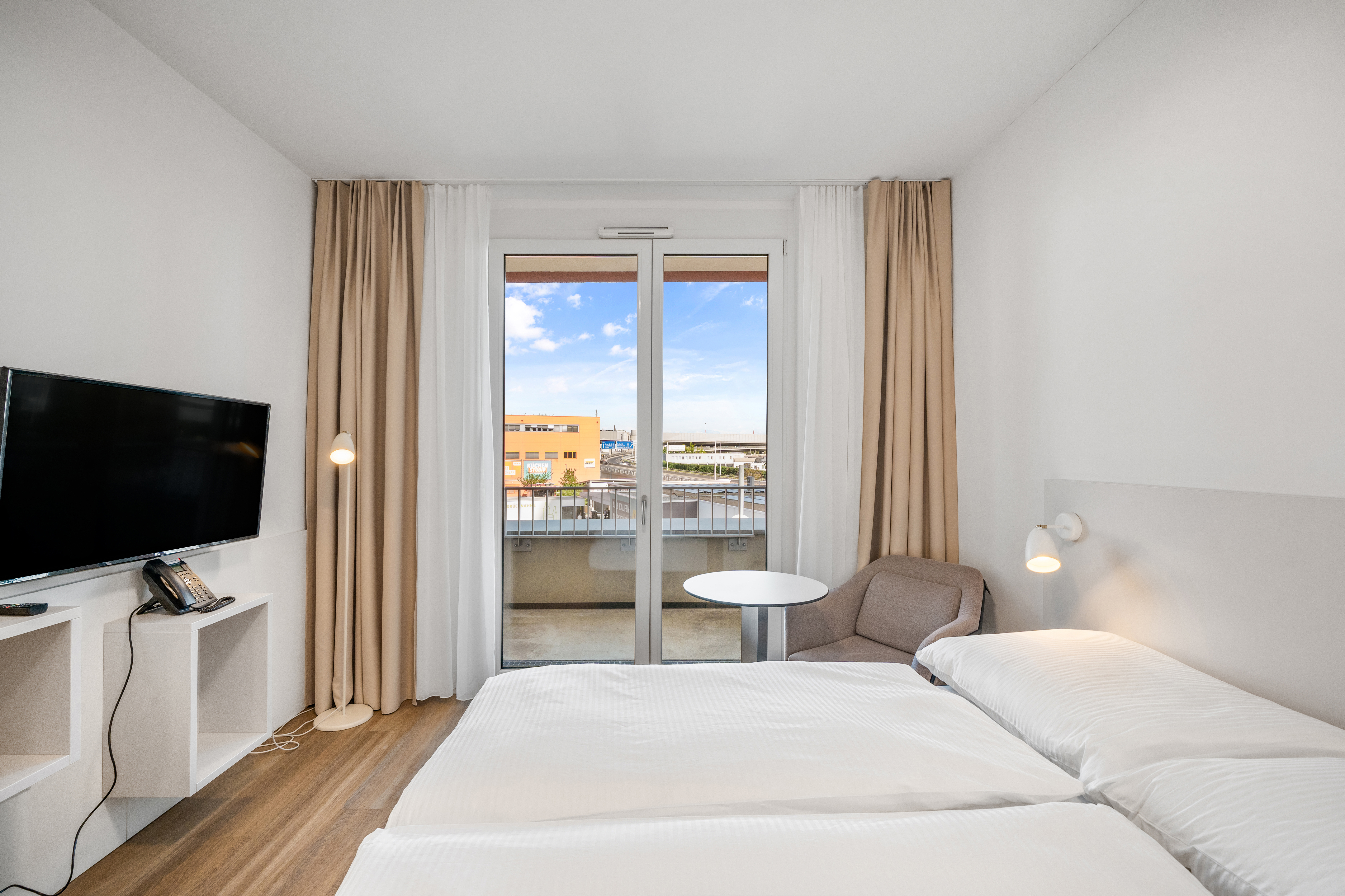 Schlafzimmer mit zwei Betten und Balkonzugang im Room4Rent Serviced Apartment Typ XS im Q-Tower