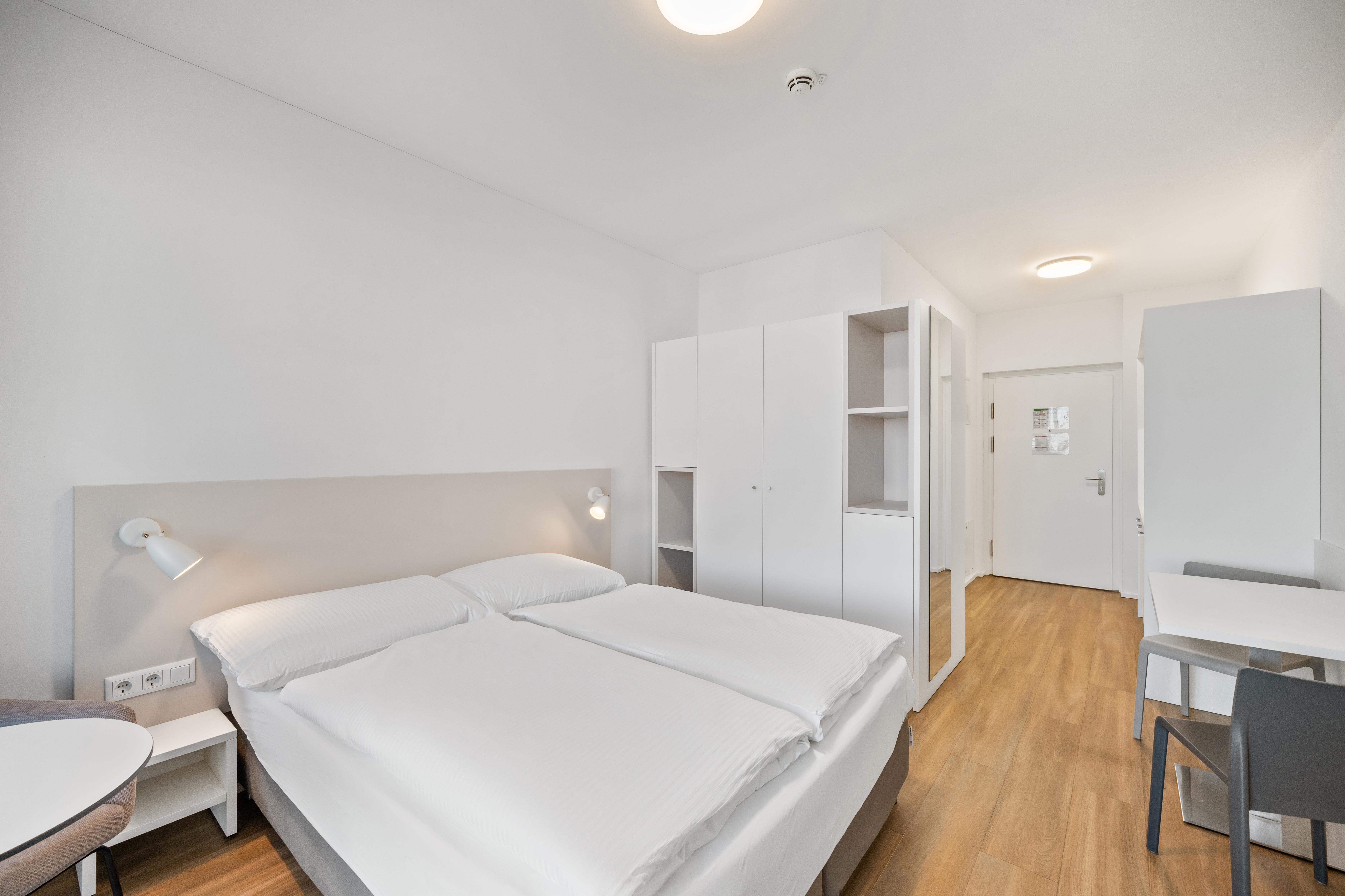Schlafbereich mit Doppelbett und Einbauschränken im Room4Rent Apartment Typ XS im Q-Tower