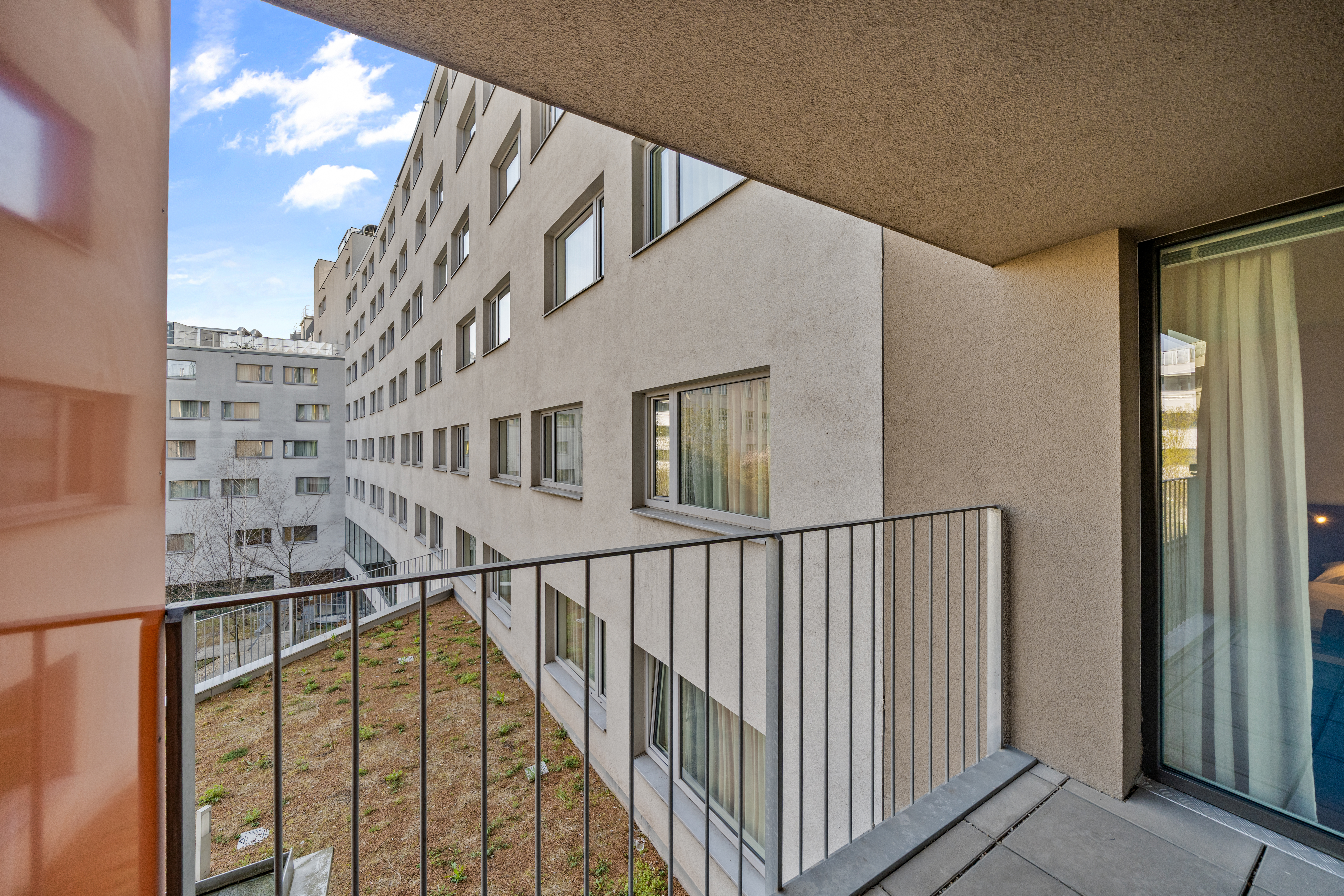 Balkon mit Metallgeländer und Blick auf den Innenhof in einem Serviced Apartment Typ M