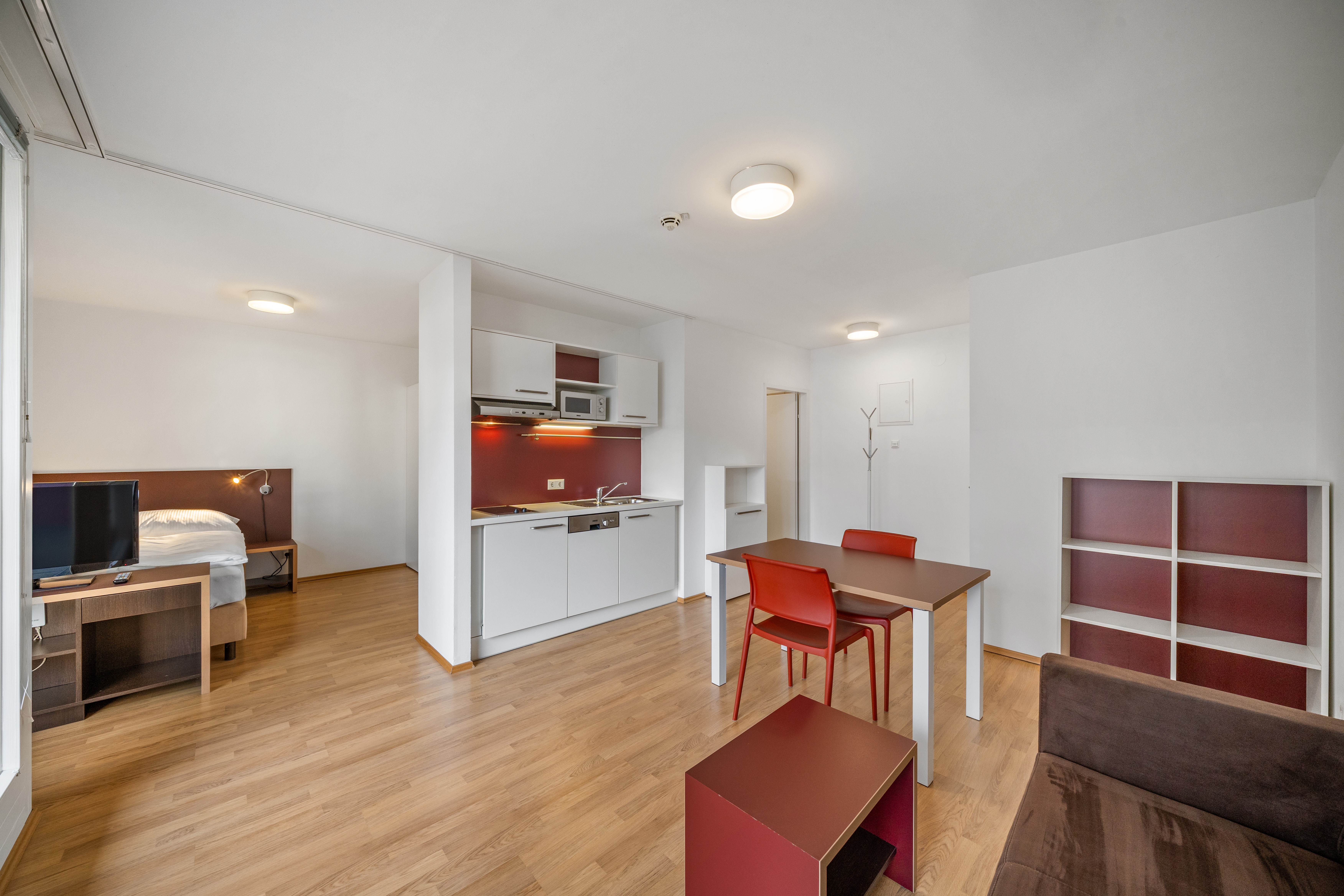 Wohnbereich mit offener Küche und Esstisch in einem möblierten Room4Rent Apartment Typ M mit Balkon