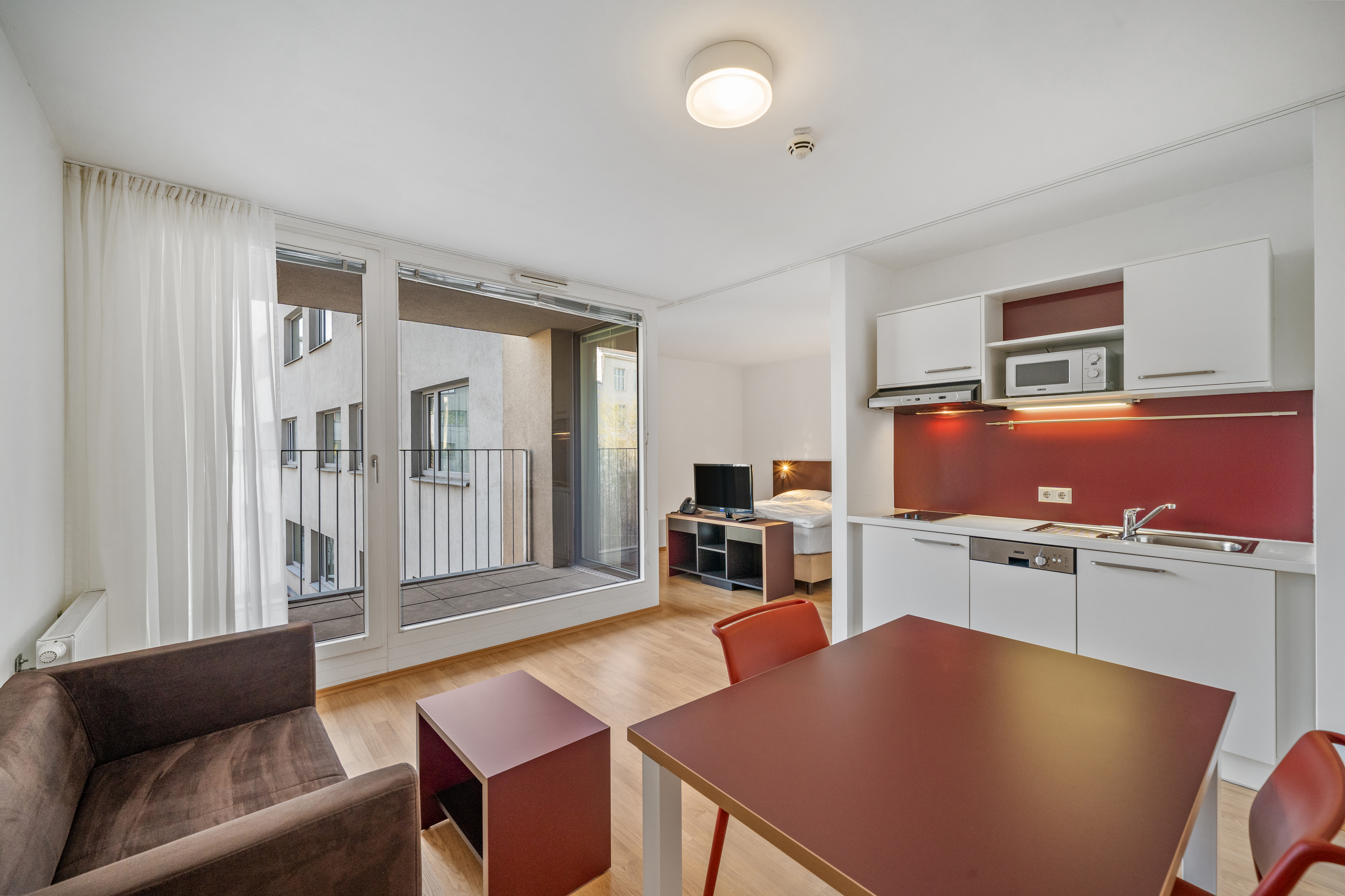 Wohn- und Essbereich mit Küche und Balkon in einem Room4Rent Serviced Apartment Typ M