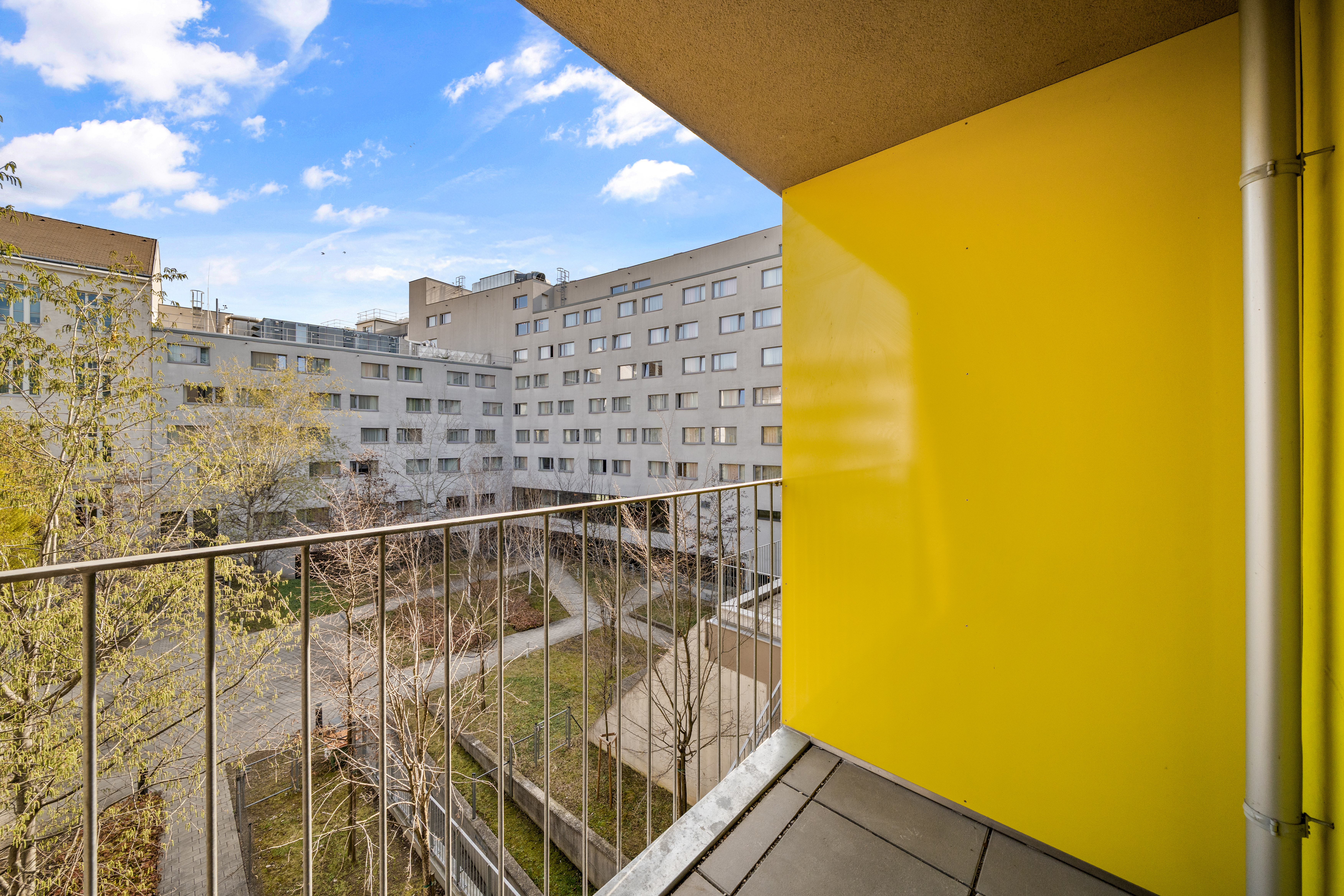 Balkon mit Blick auf einen begrünten Innenhof und Wohngebäude im Storchen&shy;grund Serviced Apartment in Wien
