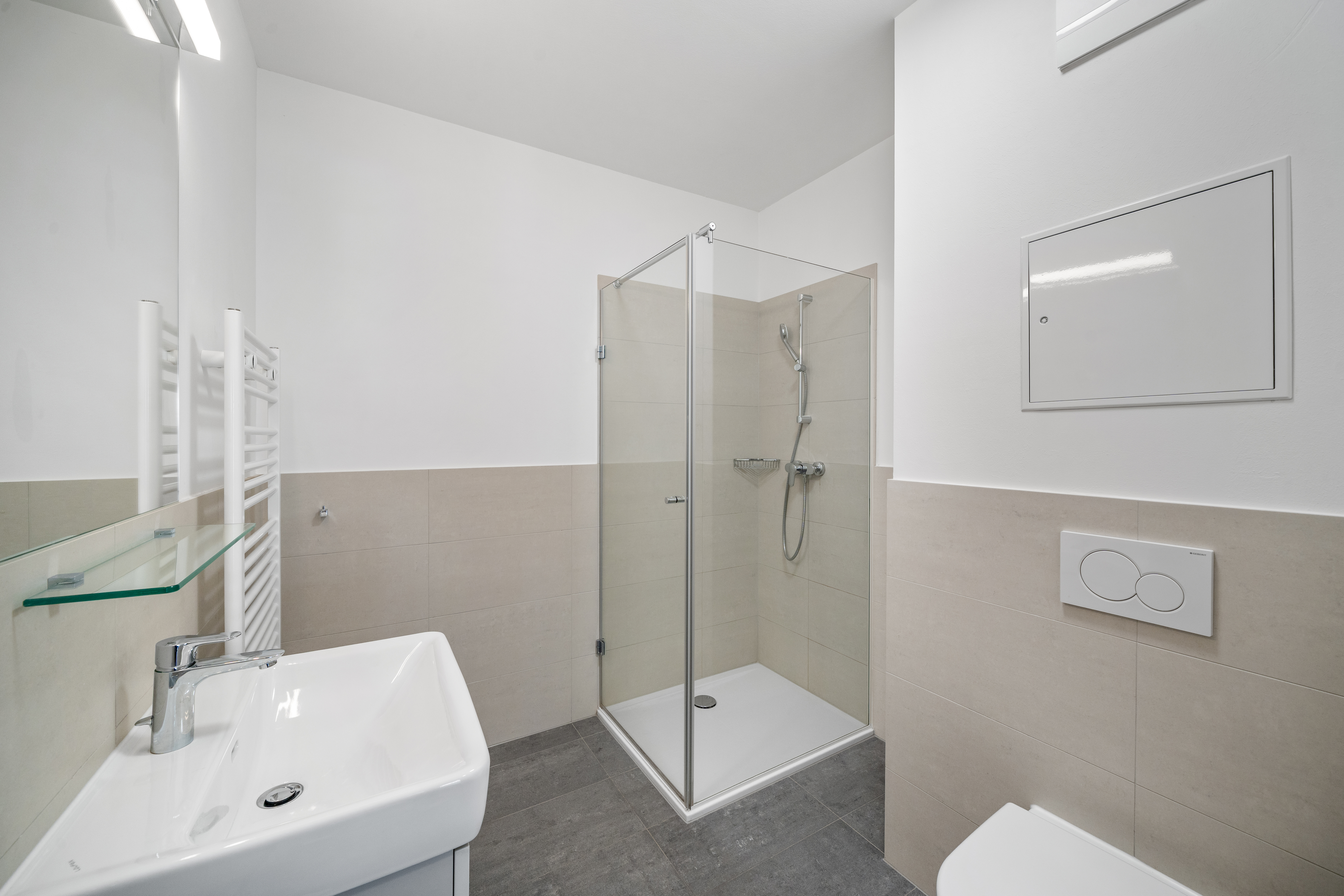 Badezimmer mit Waschtisch links, großer begehbarer Dusche und modernem Design