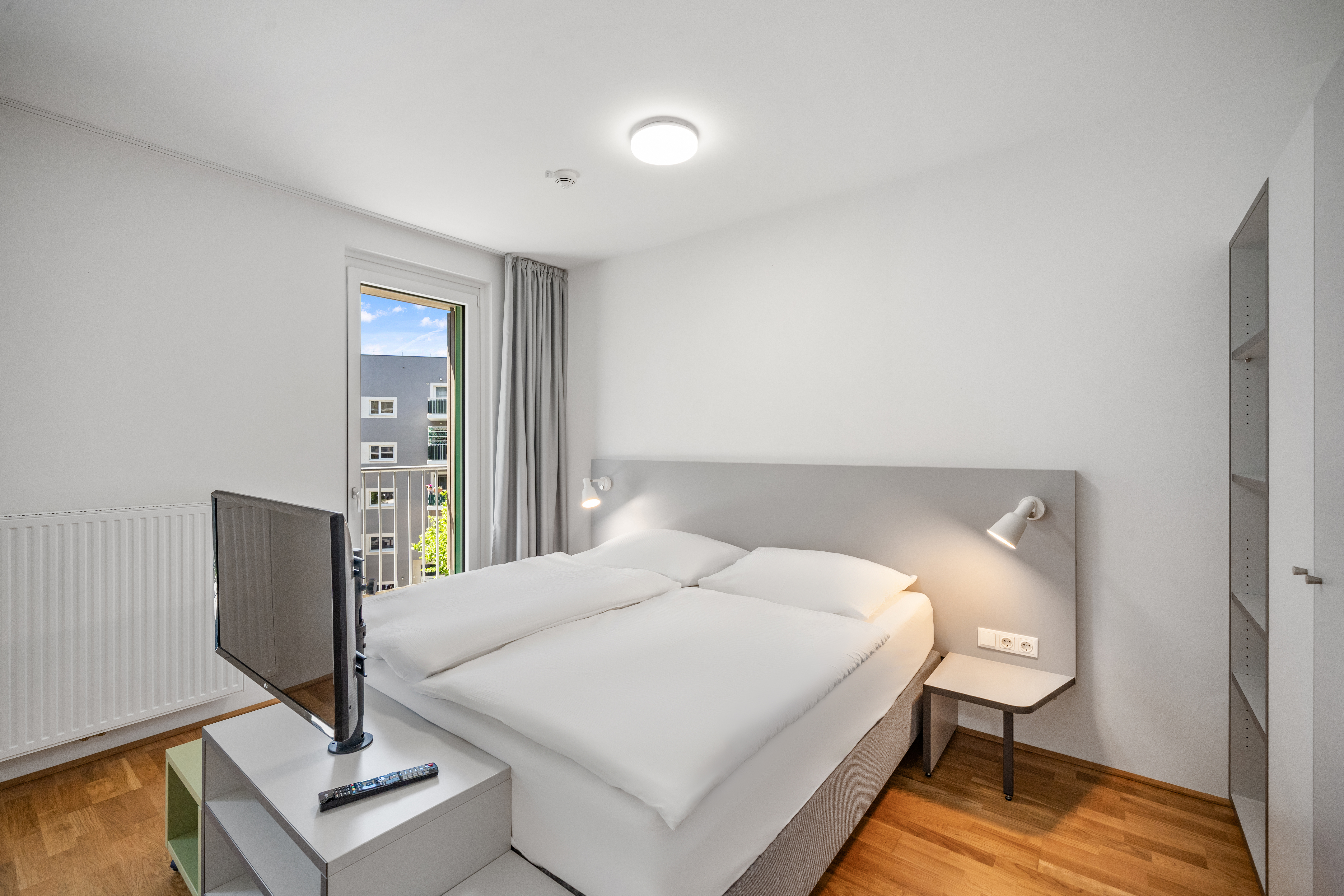 Schlafbereich mit Doppelbett und Fenster in einem möblierten Room4Rent Apartment in Wien