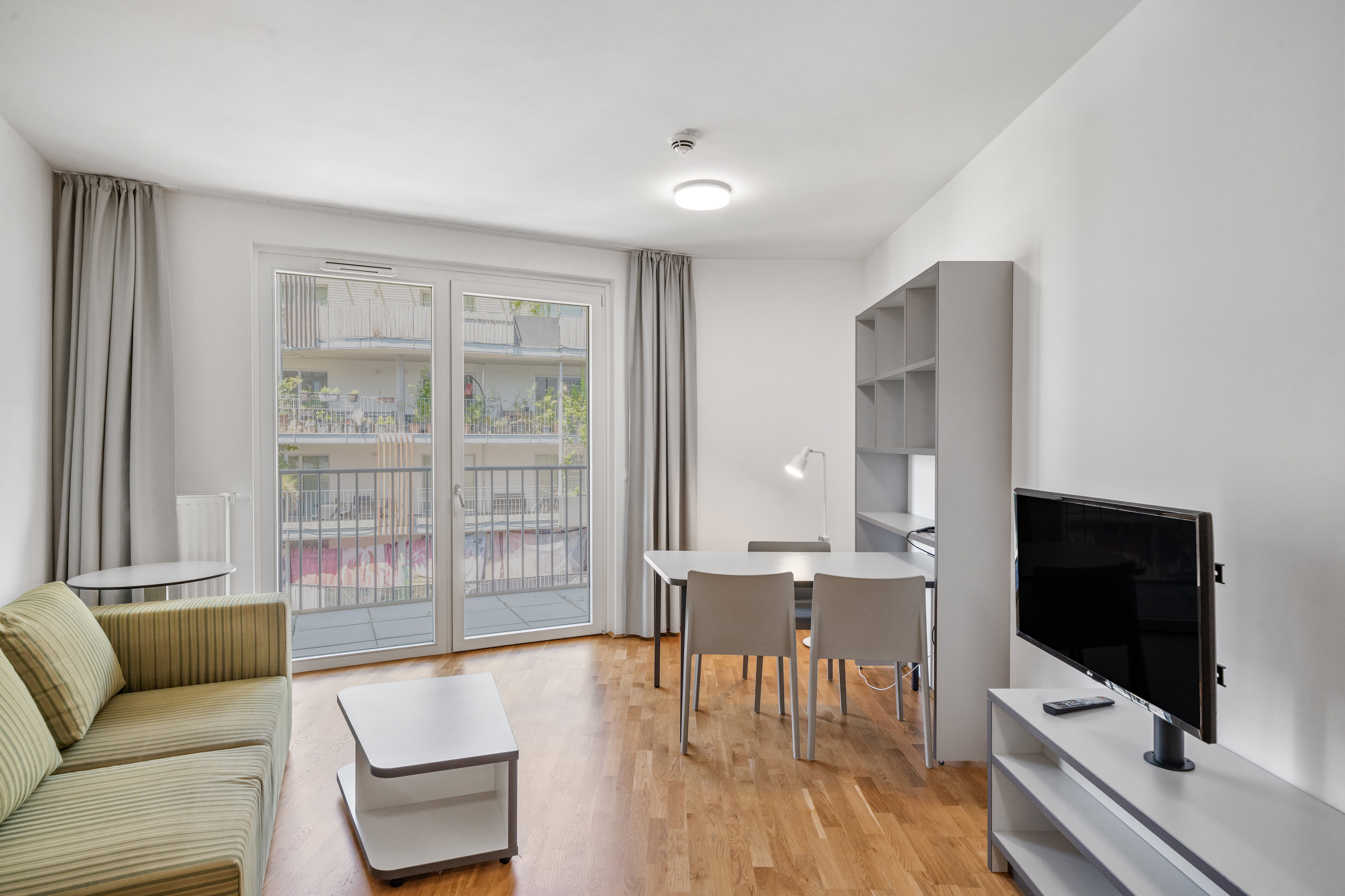 Wohn- und Essbereich mit Fernsehbereich und großer Balkontür im Room4Rent Apartment Typ M in Vienna Academic Guesthouse