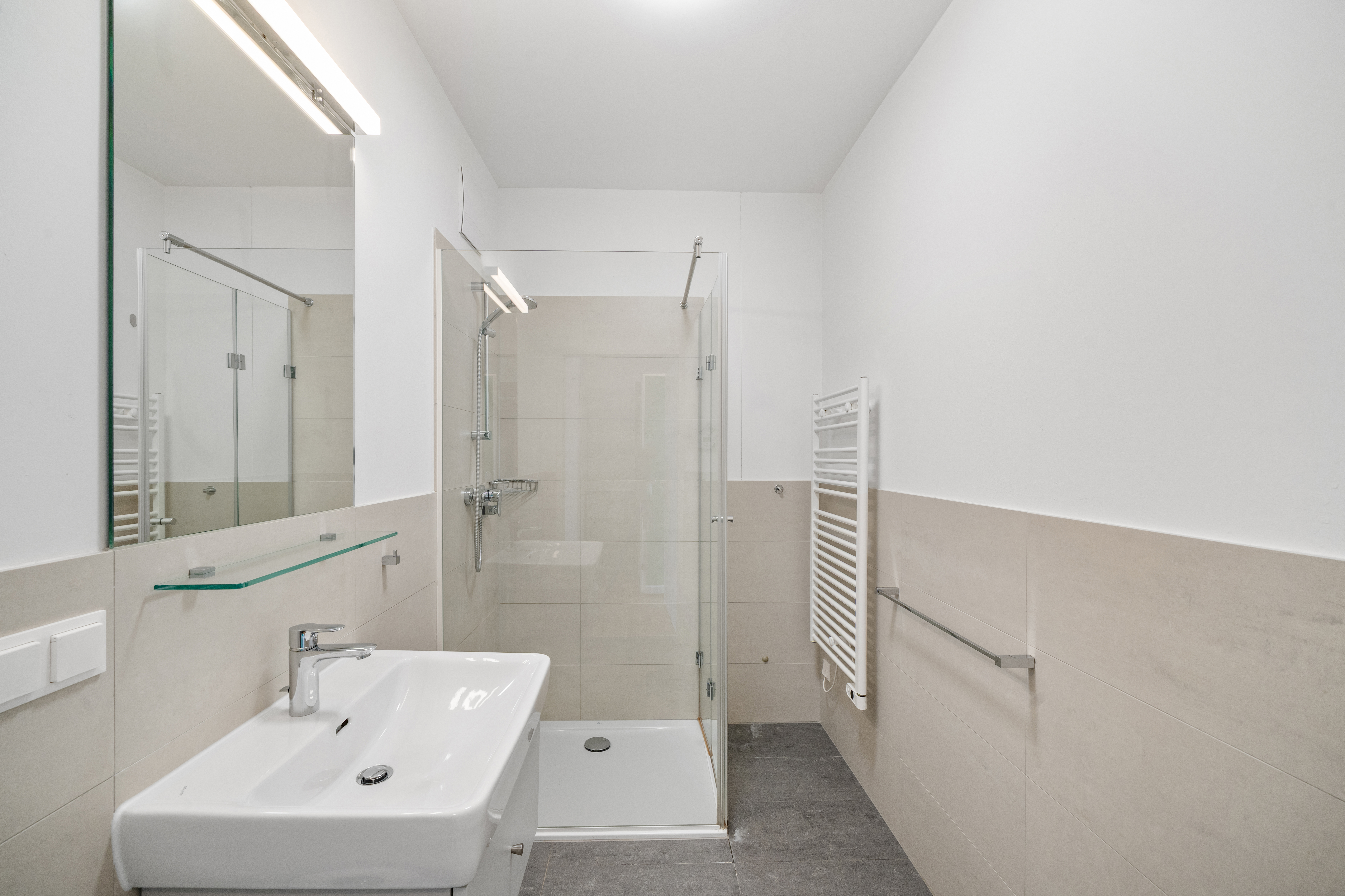 Modernes Badezimmer mit Waschbecken, großem Spiegel, Walk-in-Dusche mit Glastüren und Handtuchheizwärmer