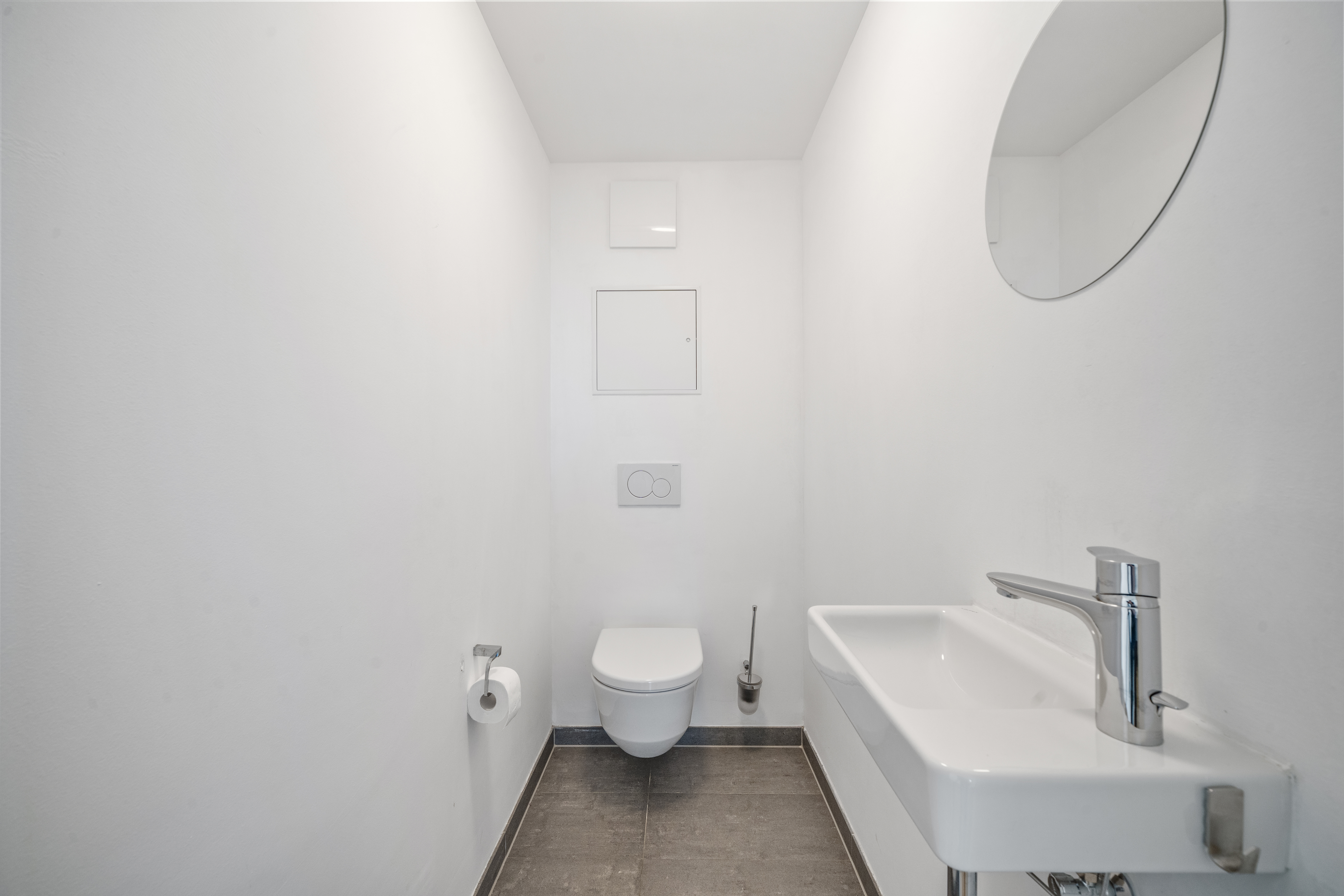 Modernes Gäste-WC mit an der Wand montiertem Waschbecken, Hänge-Toilette, Spiegel und anthrazit gefliesten Böden