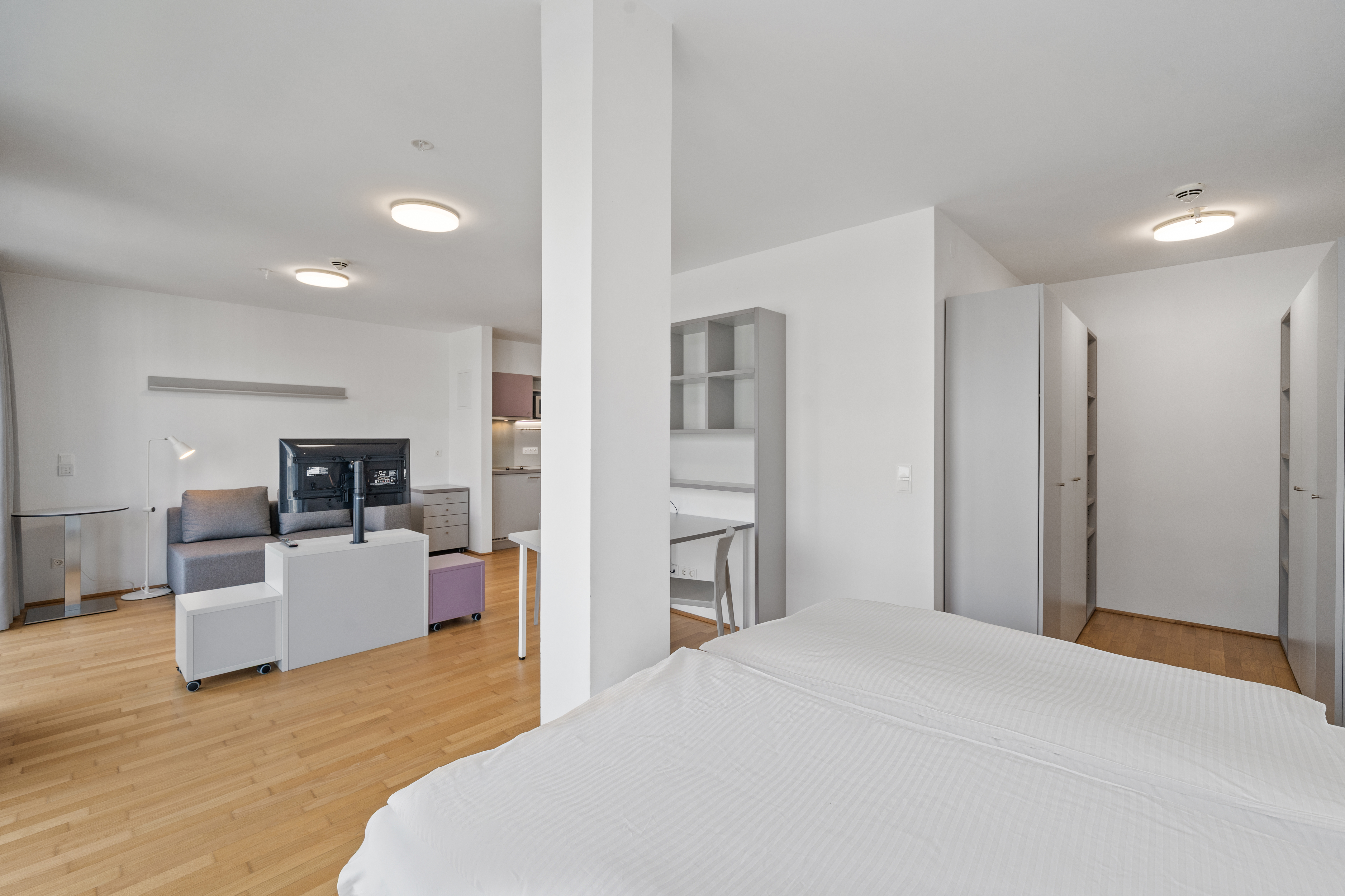 Schlafzimmer mit Doppelbett, Schreibtisch, Schiebetürschrank, modularen Boxen und Holzparkett