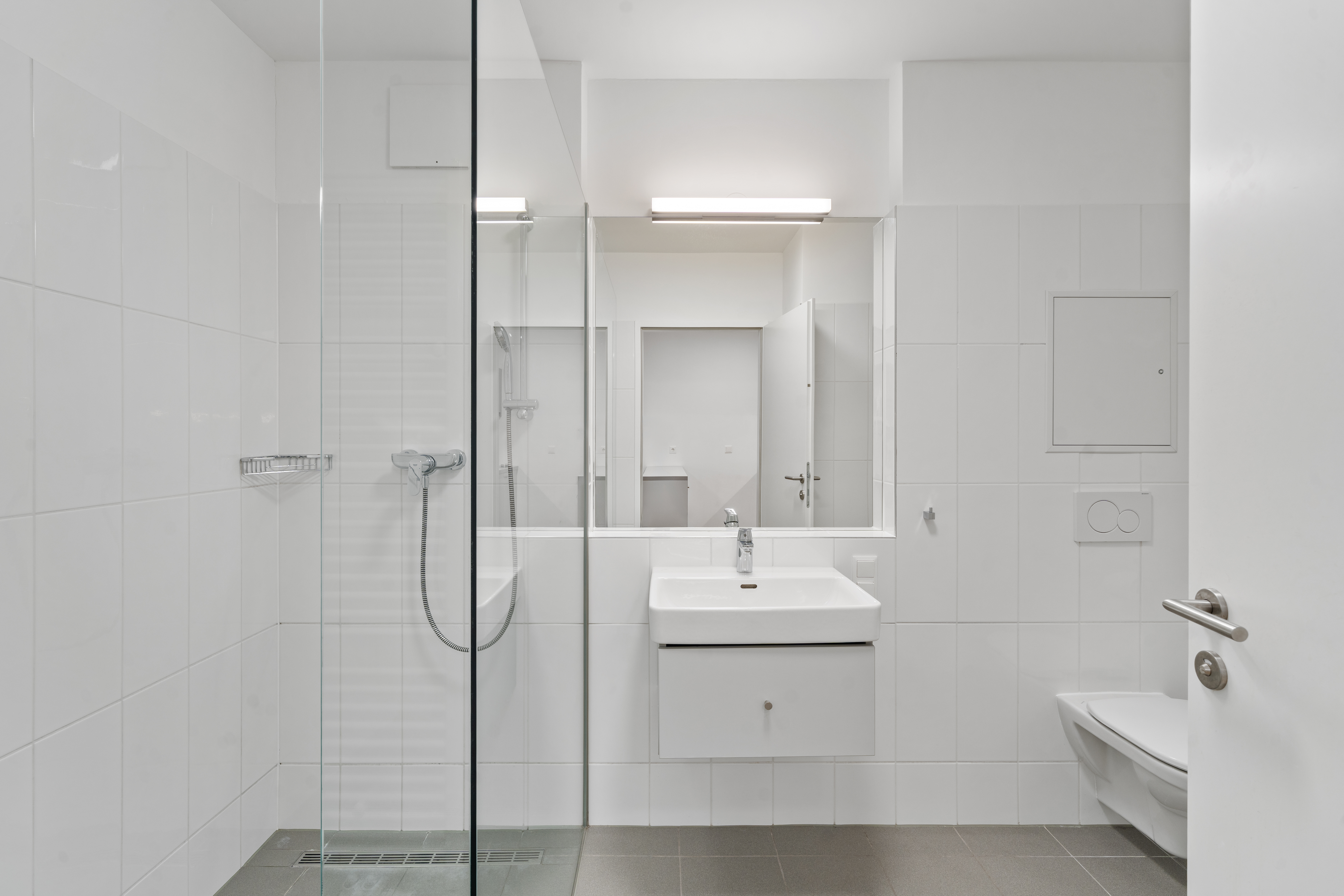 Badezimmer eines Room4Rent Serviced Apartments mit Dusche, Waschbecken und Spiegel