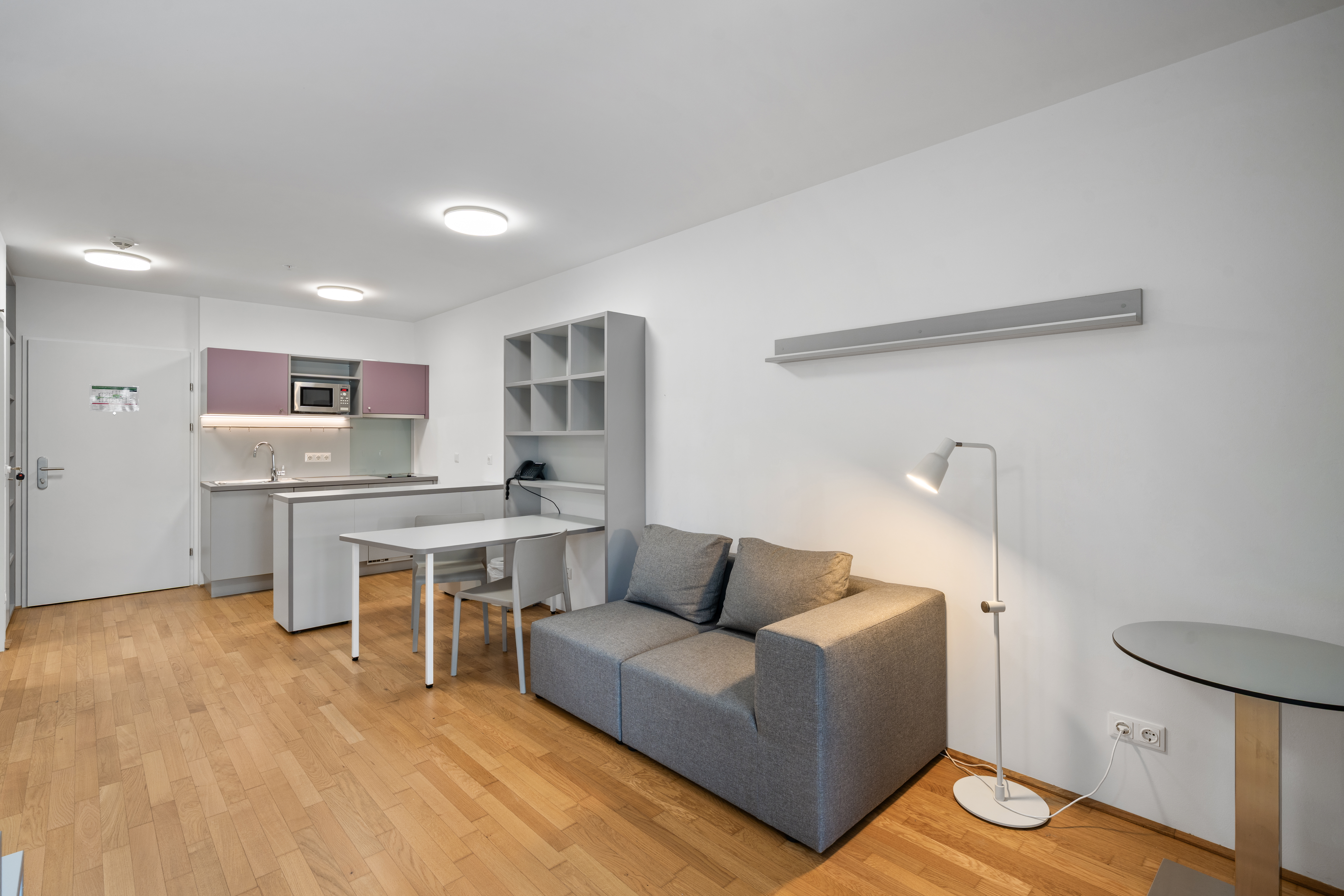Wohnbereich eines Apartment Typ S mit Sofa, Esstisch, offener Küche und Holzboden