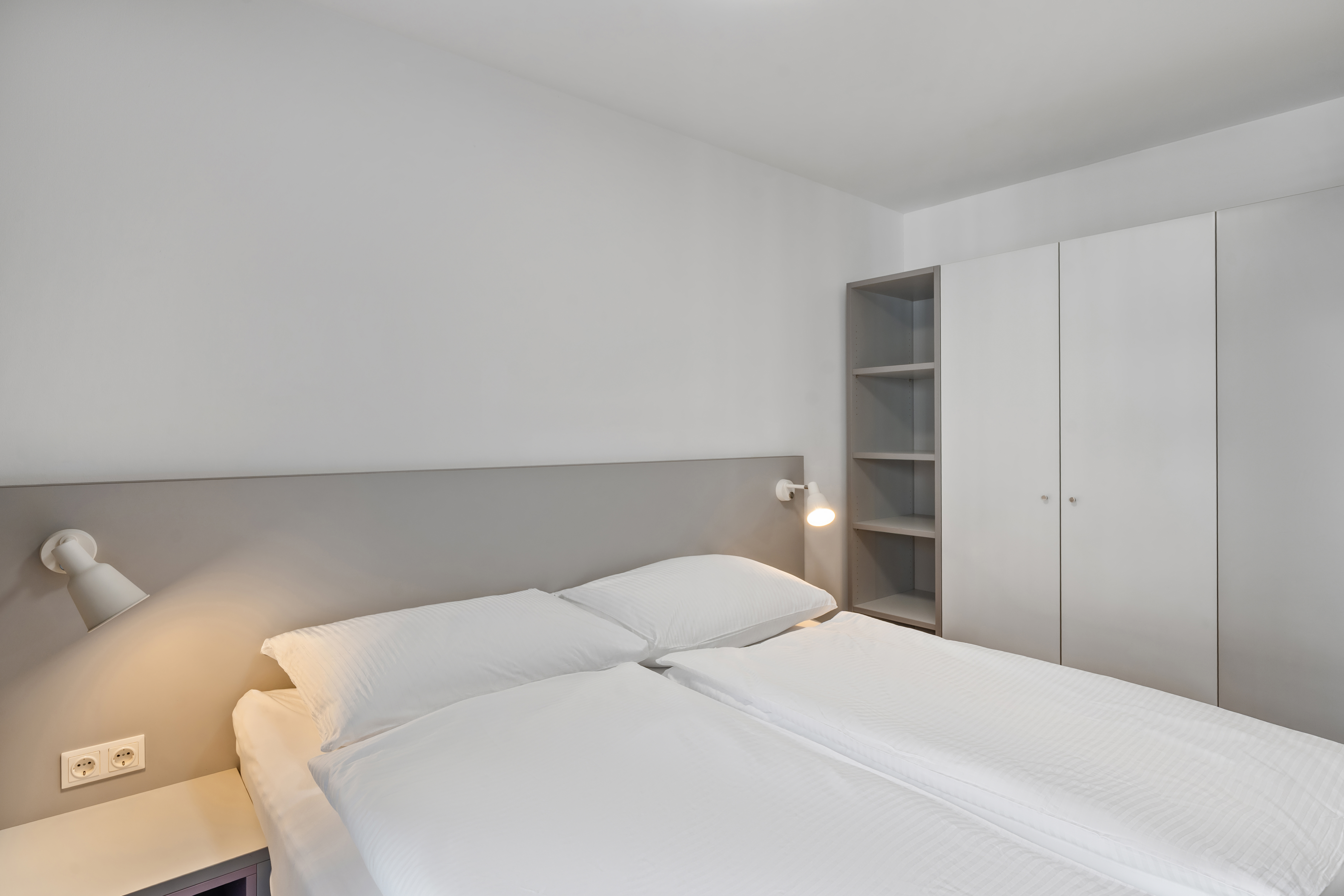 Schlafzimmer eines Apartment Typ S mit Doppelbett, Regalsystem und Kleiderschrank